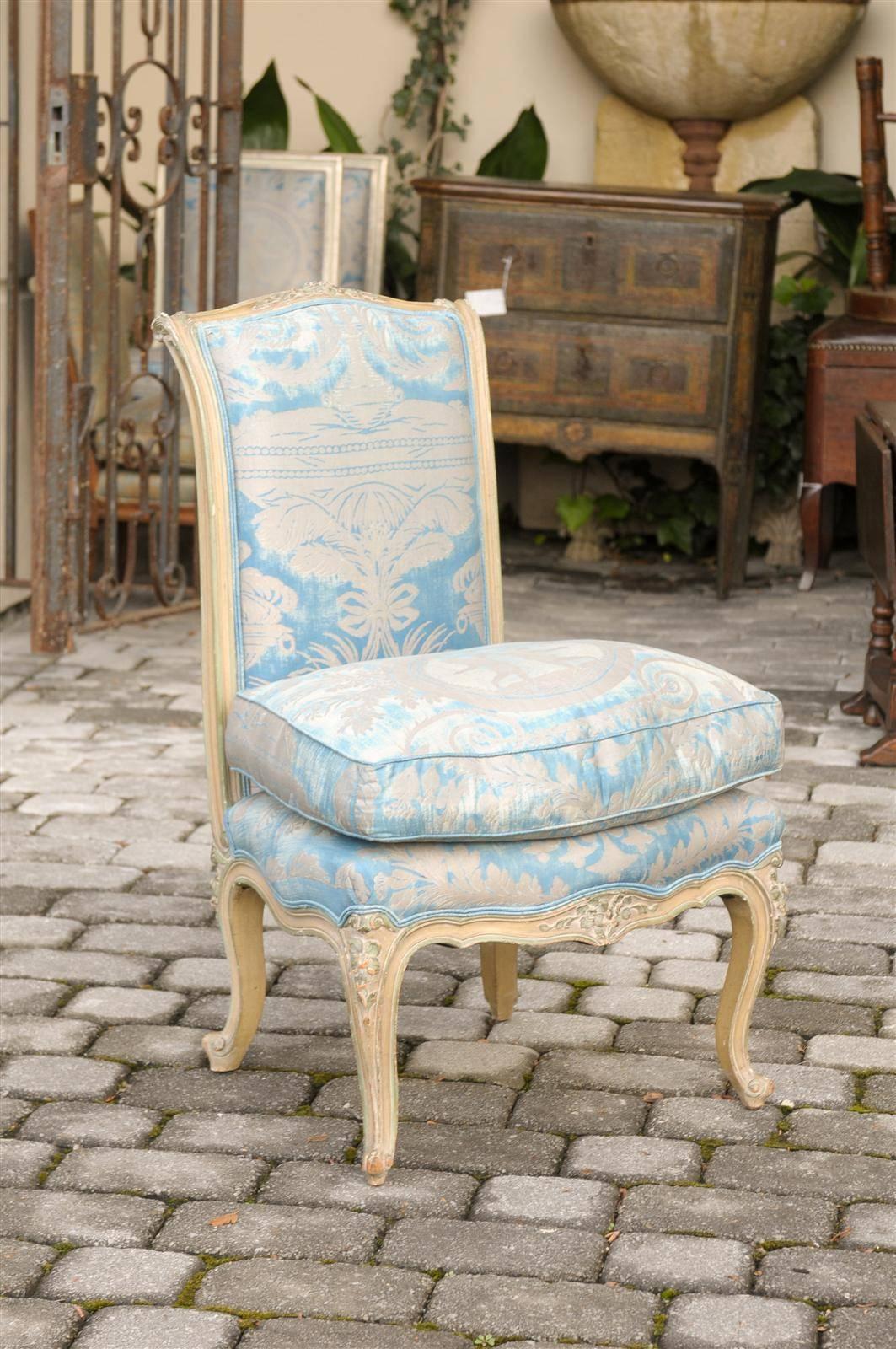 A Louis XV style French painted slipper chair in Fortuny fabric with cushion. This exquisite French painted wood slipper chair from circa 1930 features a delicately carved scrolled back. The chair is raised on short cabriole legs carved on their