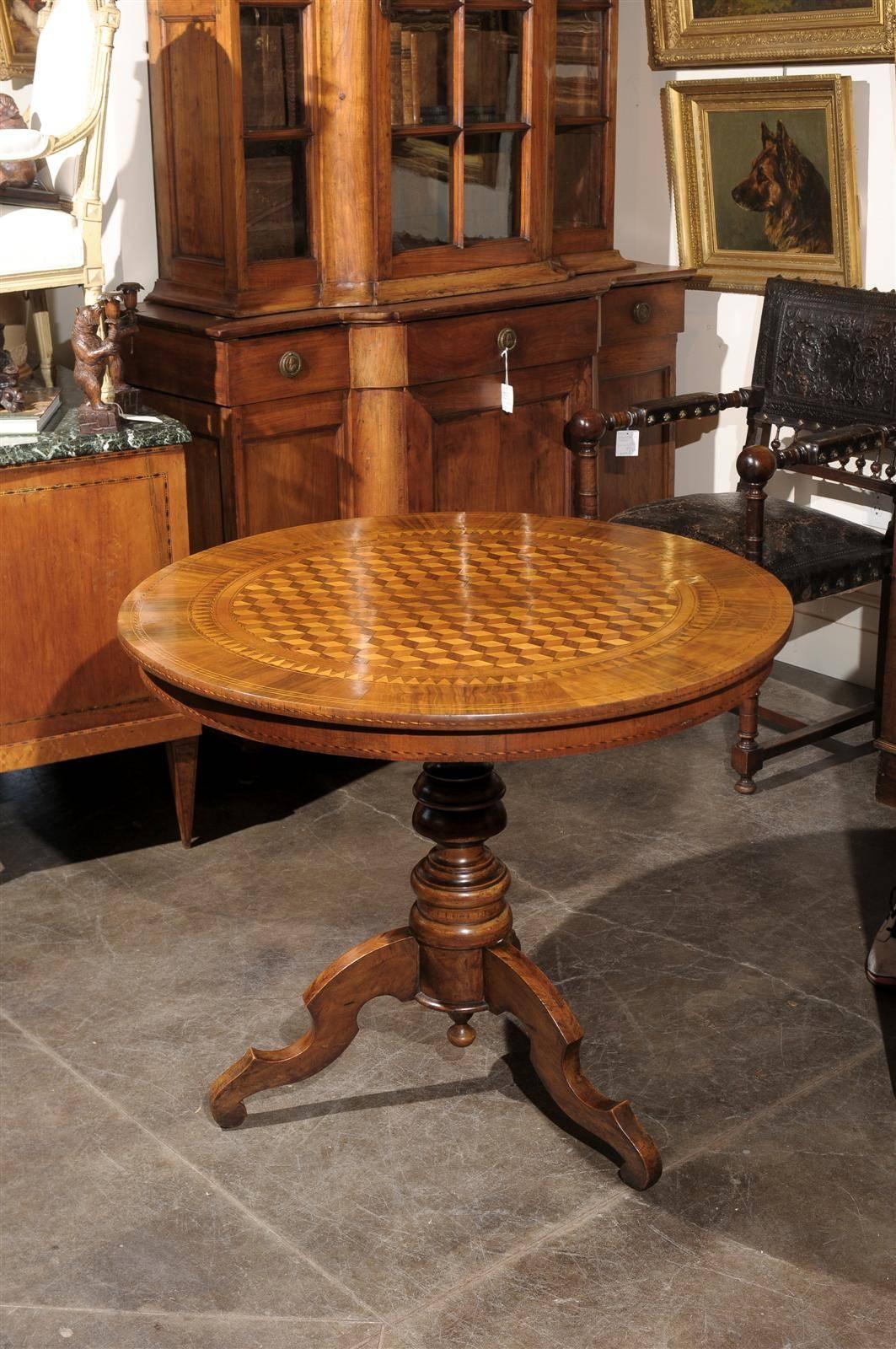 This Italian round pedestal wooden table from the mid to late 19th century features an exquisite cube parquetry inlay on the top, surrounded by a variety of motifs in the surround. The wood grains, delicately placed between the decorative motifs,
