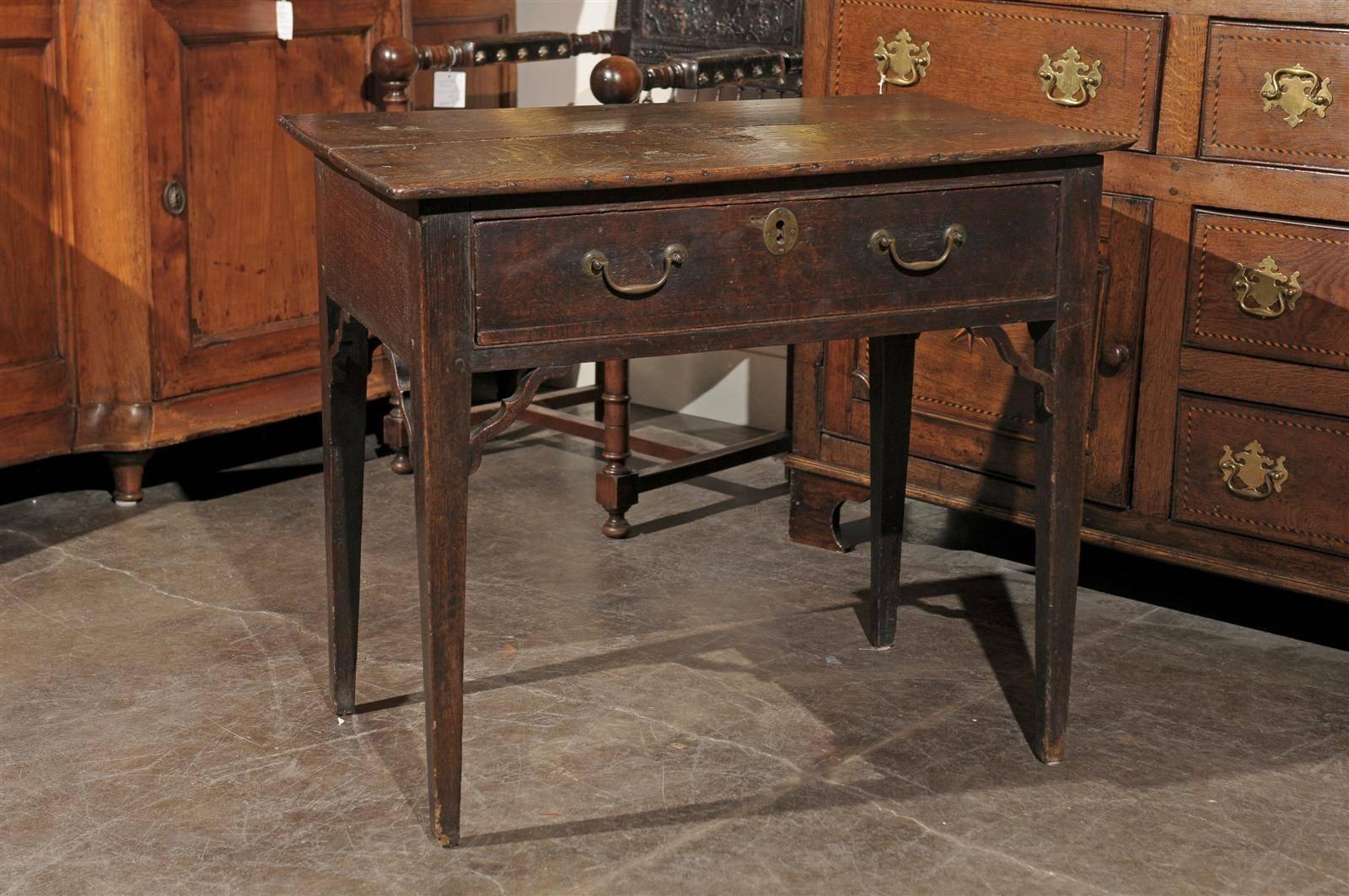 A period Sheraton oak side table with drawer from England from the 1780s. This stylish English oak side table features a rectangular top over a simple apron, adorned with a single drawer and two elegant bail handles and a central escutcheon. It