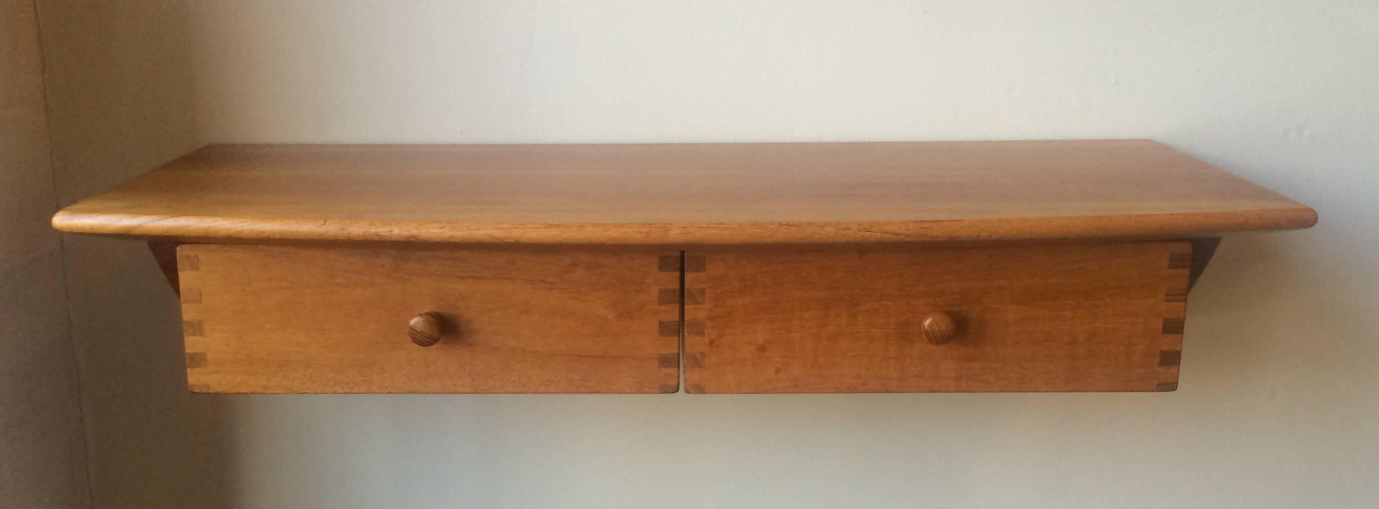 Solid teak construction wall console with a crescent shaped top and two drawers with finger joinery, a simple yet elegant design.