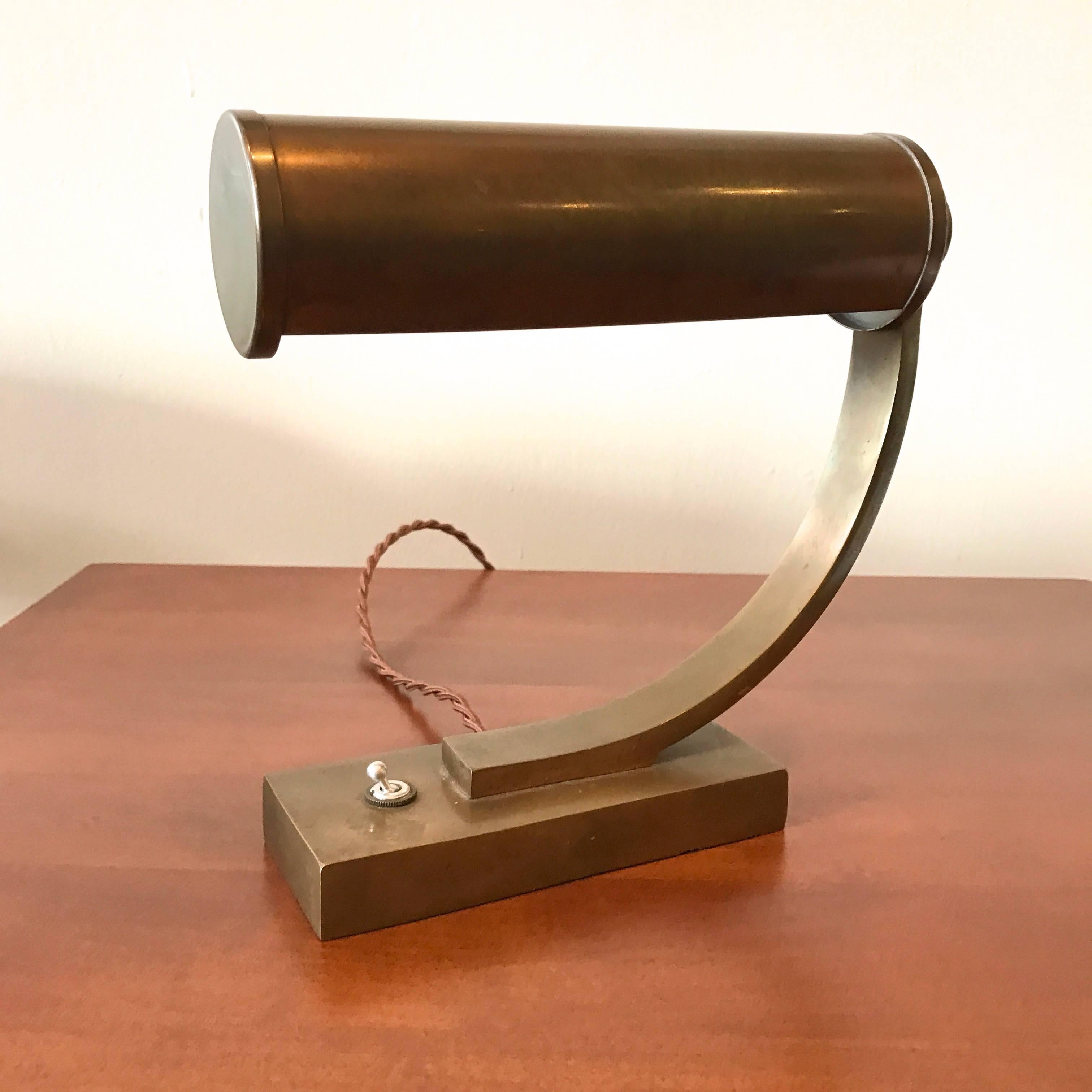 Brass Machine Age design desk lamp with a cylindrical adjustable shade resting on a weighed plinth base with a toggle switch and newly rewired. Great soft lustre patina to brass finish.