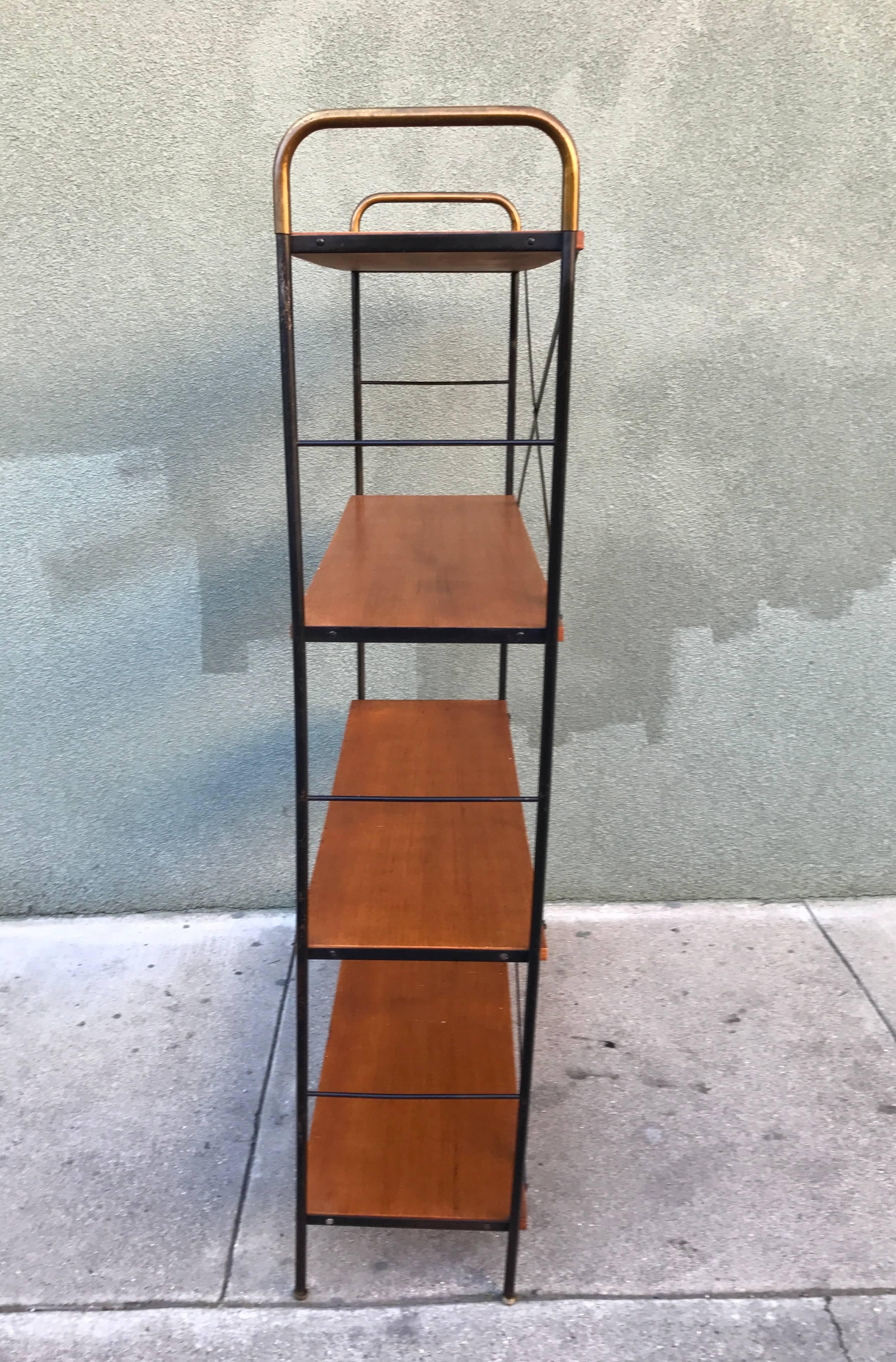 Early 1950s Vista of California shelf unit constructed of a painted iron frame, oiled mahogany shelves with brass accents and adjustable glides to compensate for uneven floors. All original condition with patina to paint and wood surfaces. Nice