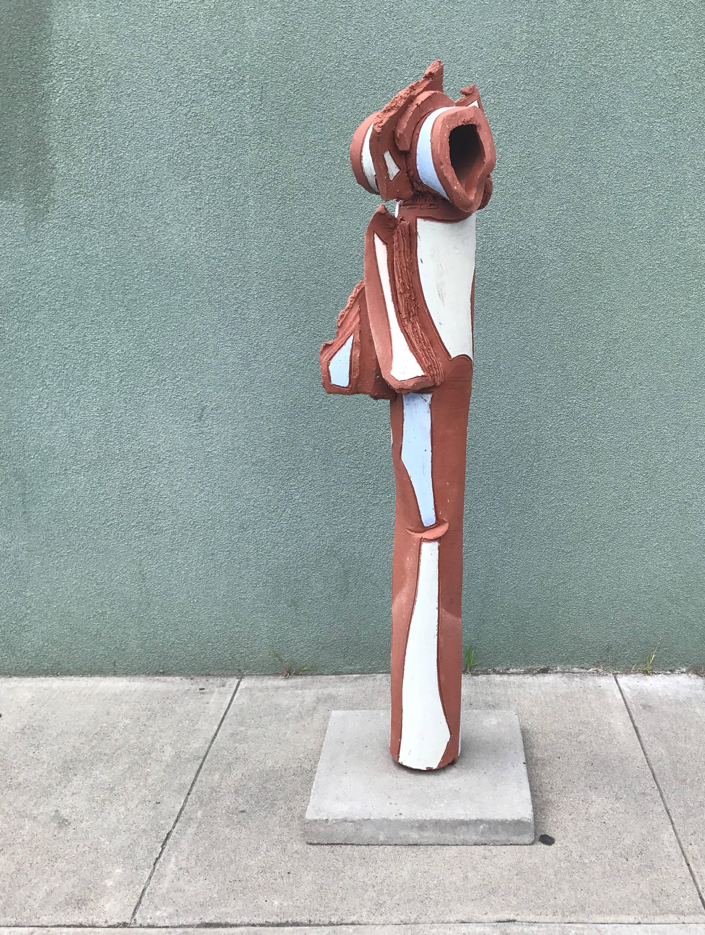 Large ceramic abstract or Brutalist sculpture in a natural red tone fired clay with selectively applied glazes, a cylindrical form in which the clay has been carved to create both repeating form and texture on its surface. The base is a grey tone