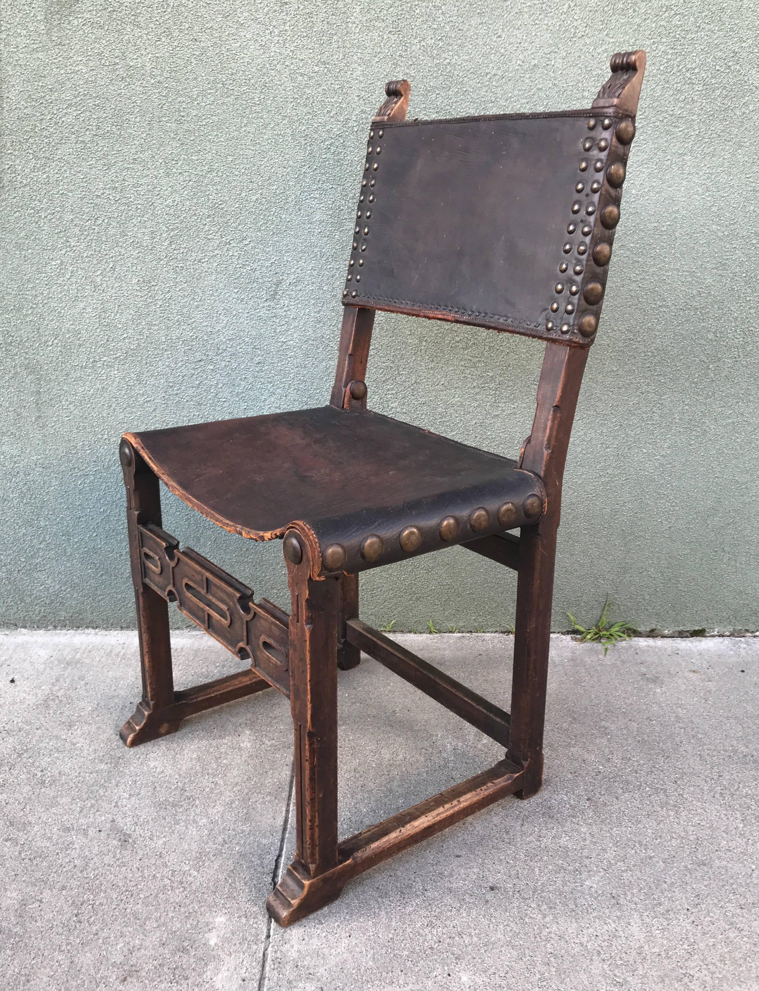 Spanish Revival chair from the 1920s carved accents to the wood with brass medallions on the sides and front, much patina to the chair, very rustic in nature.