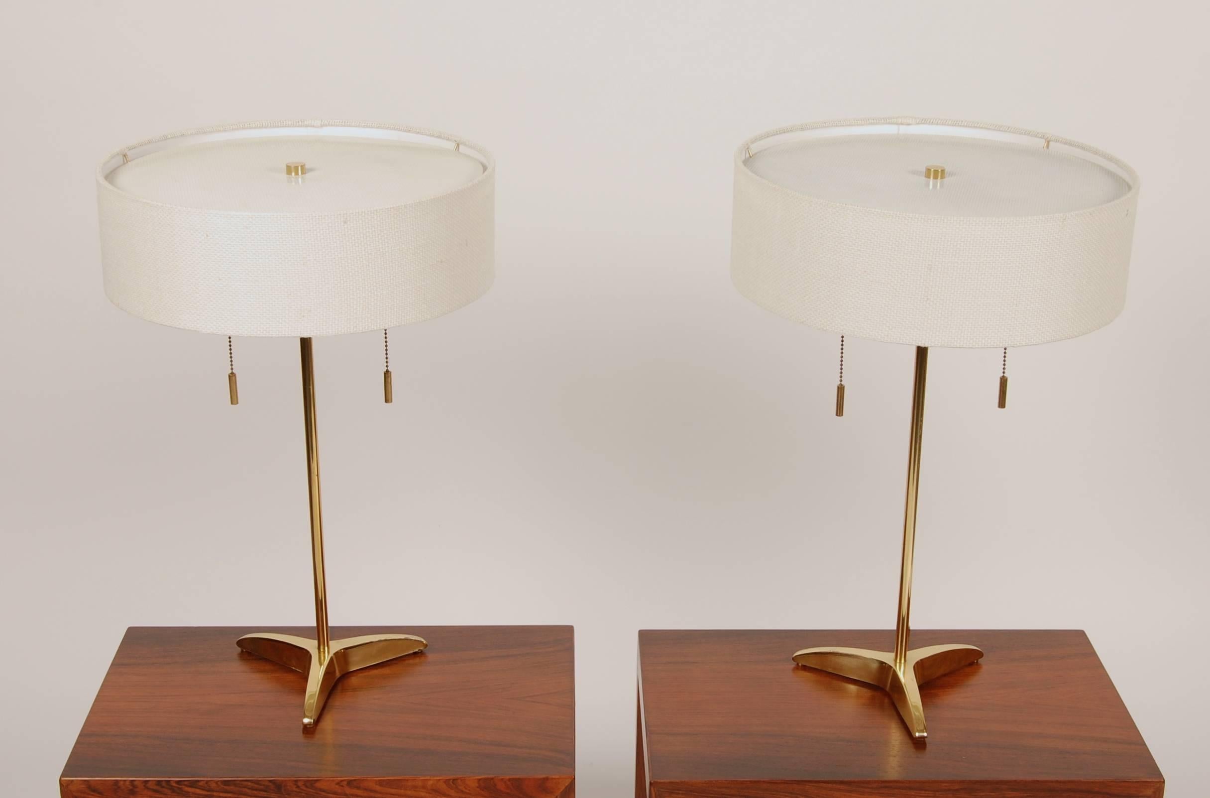 Matching brass table lamps by Stiffel of the United States, resting on angular tripod bases with slender stems that collimating to delicate linen drum shades and is topped by perforated metal diffusers. With new custom shades and rewired, each lamp