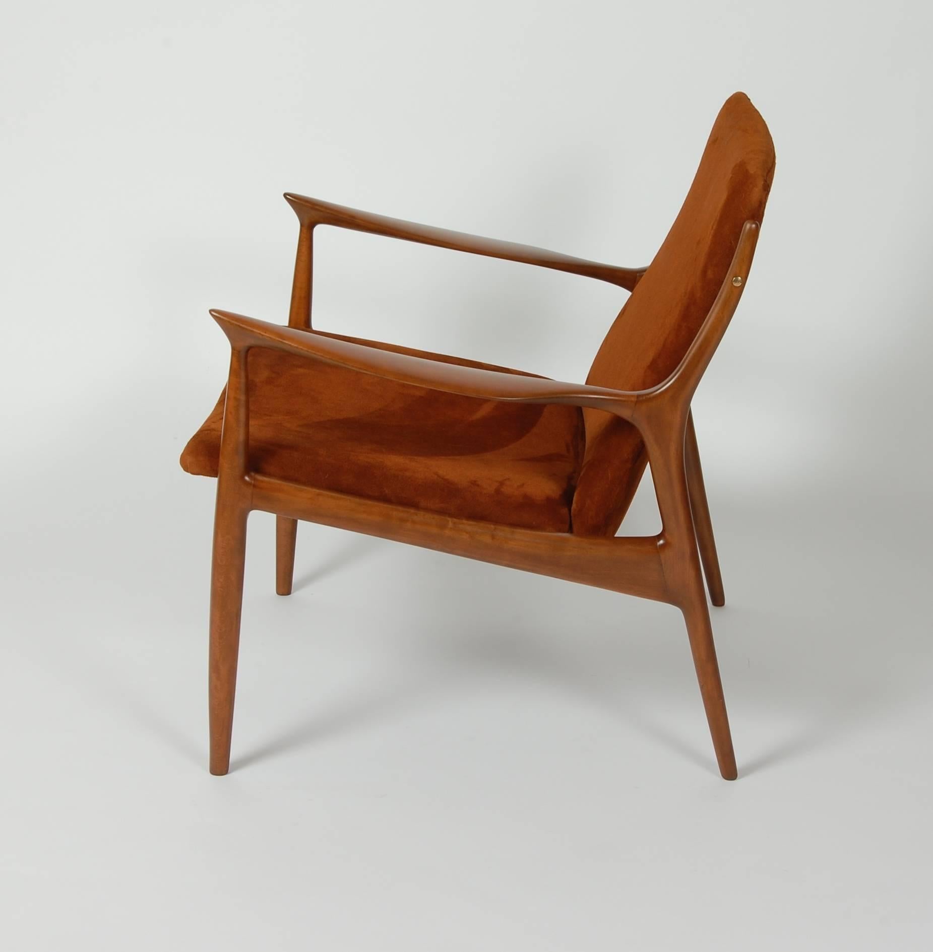 Sculptural armchair by Ib Kofod-Larsen for Selig of Denmark. Newly refinished and upholstered in a rust colored suede. The angled arms start with a severe point and end in a organic taper. Bass accent fasteners for the backrest add a nice visual