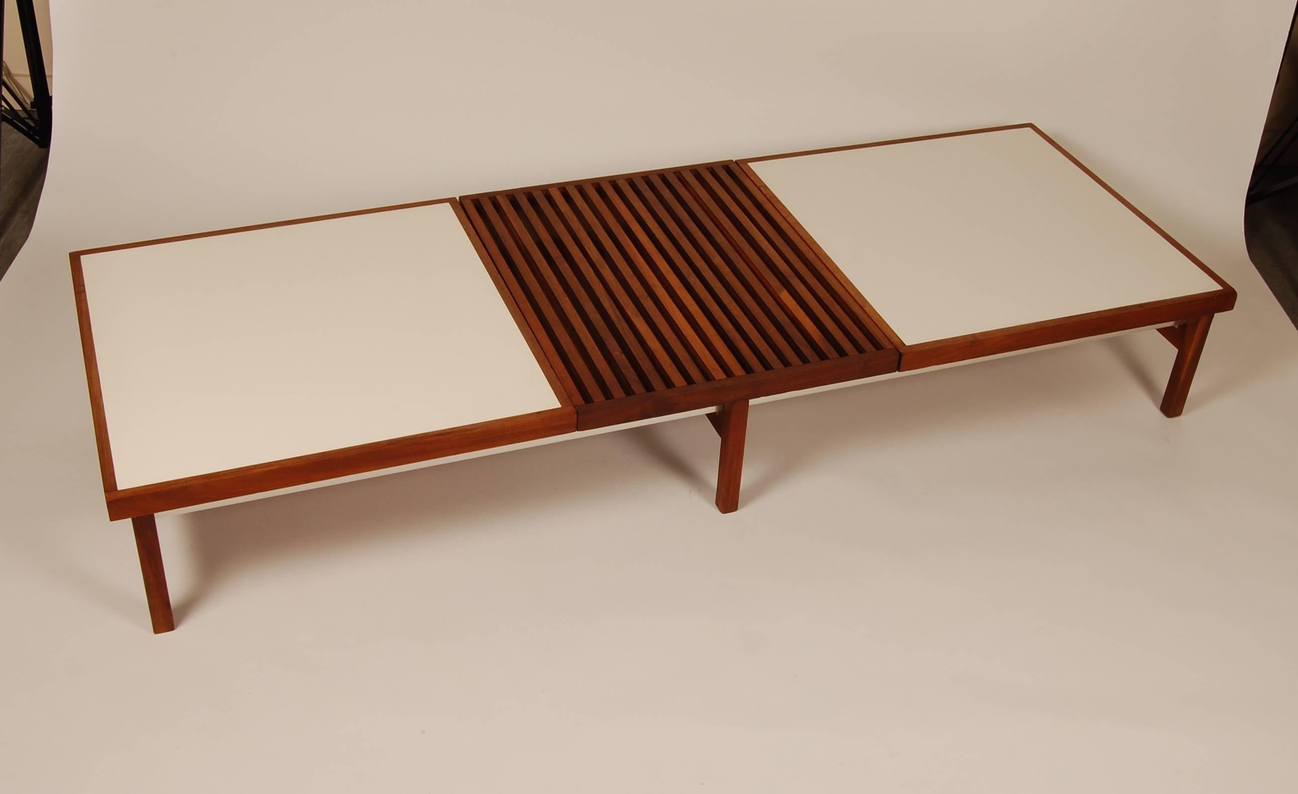 A very interesting modernist bench / coffee table with all the characteristics we like: Over-designed and over-crafted. The frame consists of two parallel milled aluminum L tracks supported by three sets of walnut legs attached via a series of