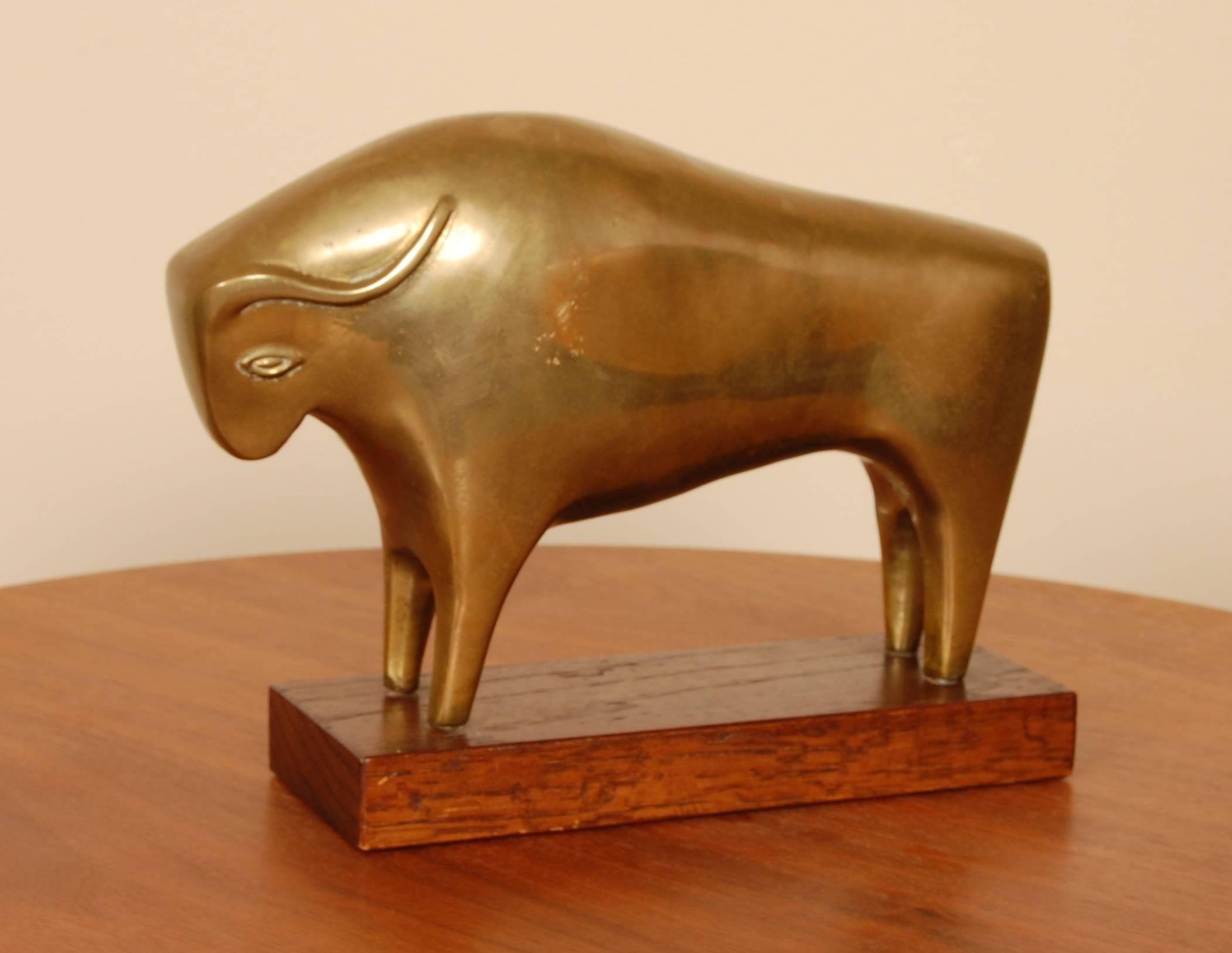 Brass abstract sculpture of a bull mounted on a wooden base. The body is of solid brass with very clean lines to define the form of the animal and the base is of a oiled mahogany.