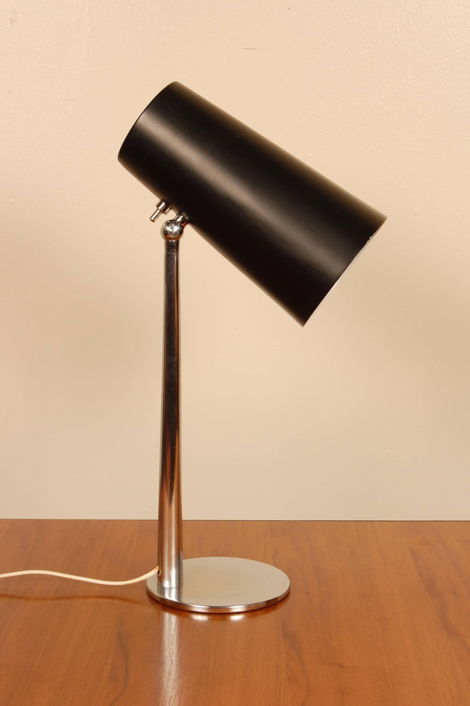 Italian table lamp with a conical black lacquered aluminum shade on a chromed base that allows for the adjustment of the light direction.