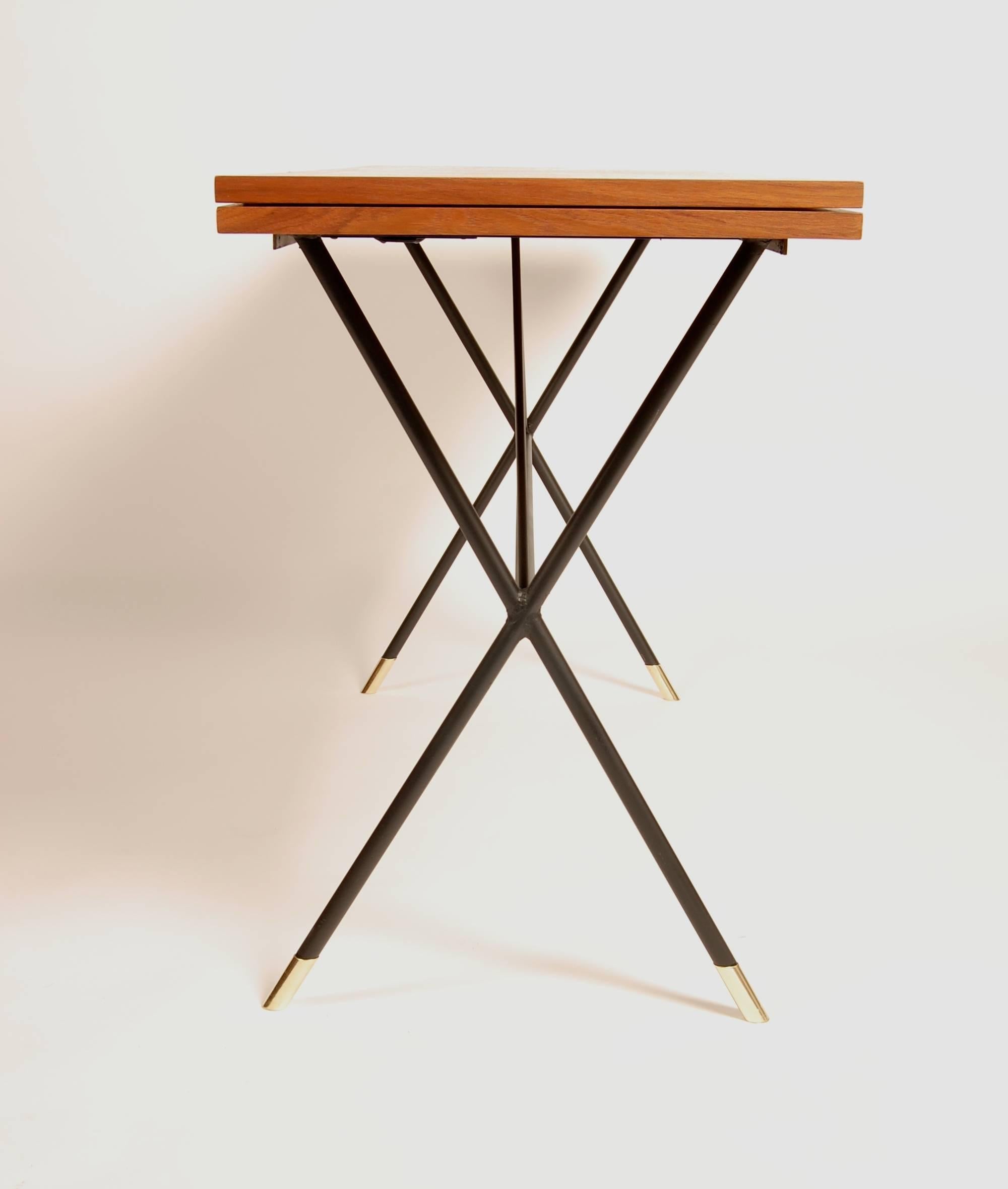 Modernist dual function console table that converts to a dining table. The iron X - base frame has an architectural approach to its design and is neatly finished with brass sabots. The teak top has amazing graining with very pronounced Cathedrals