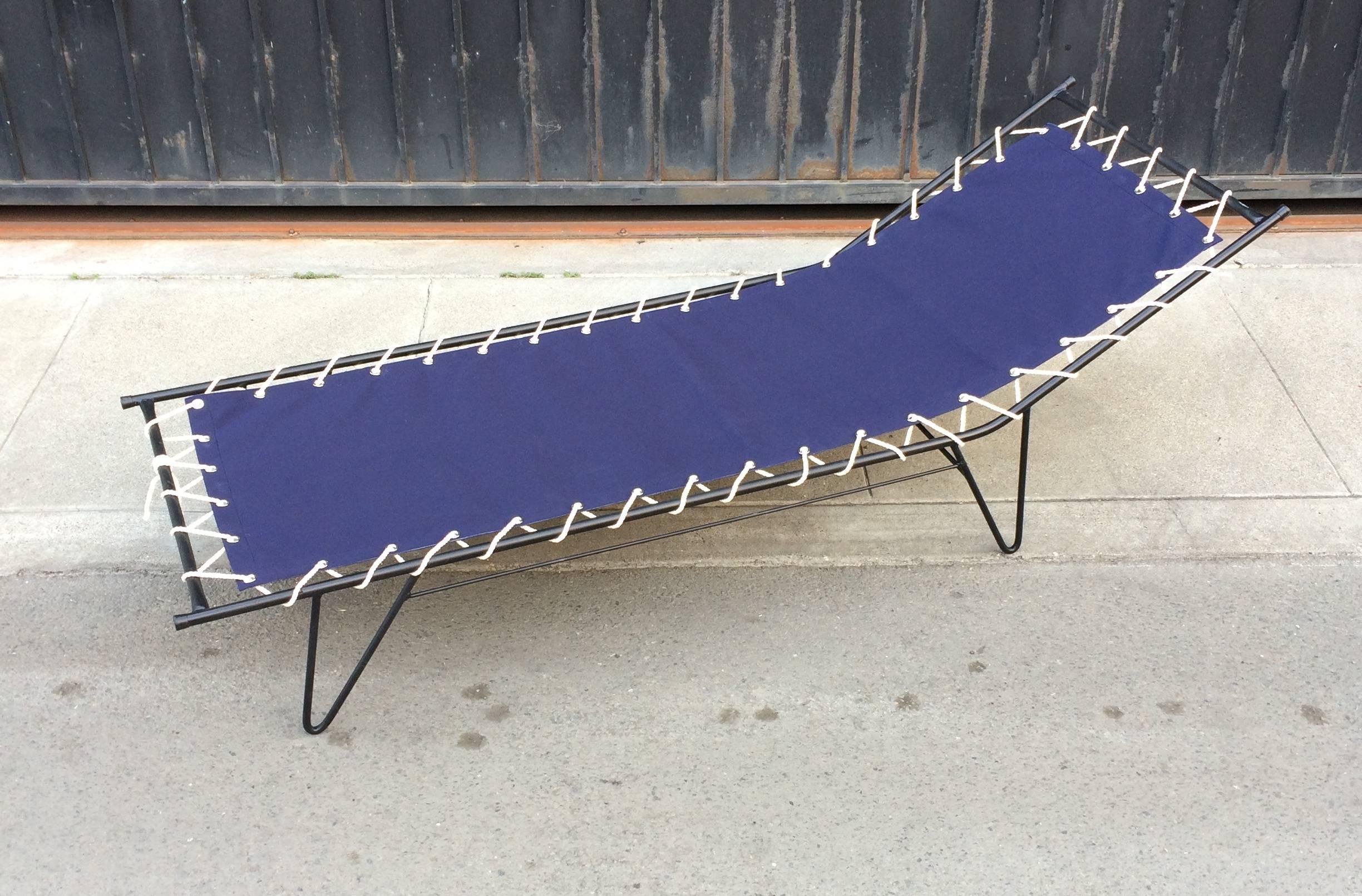 1950s iron tubed framed chaise with new dark navy canvas sail cloth upholstery with nickel eyelets and cotton cord. The frame has been resprayed with a rust proofing paint in a satin black.