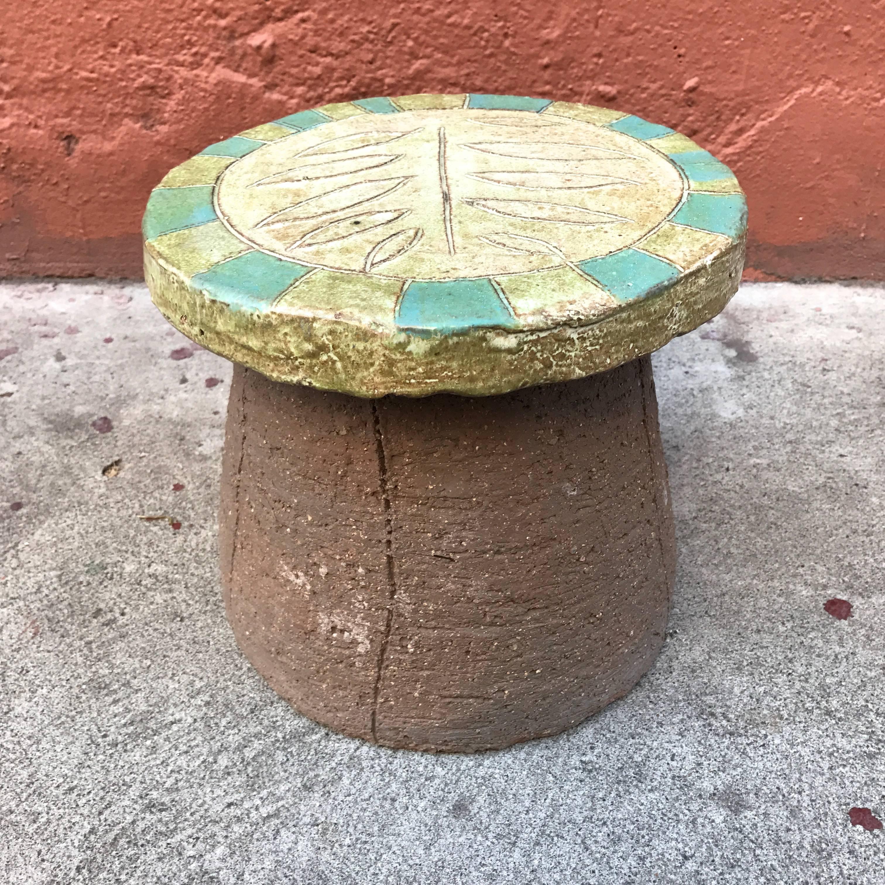 Low ceramic leaf motif stool by California ceramic artist Stan Bitters for Hans Sumpf. The top has a soft light green glaze to the leaf pattern and the trim details have a green and blue/green glaze blocks of color. Bitters born in 1937 studied