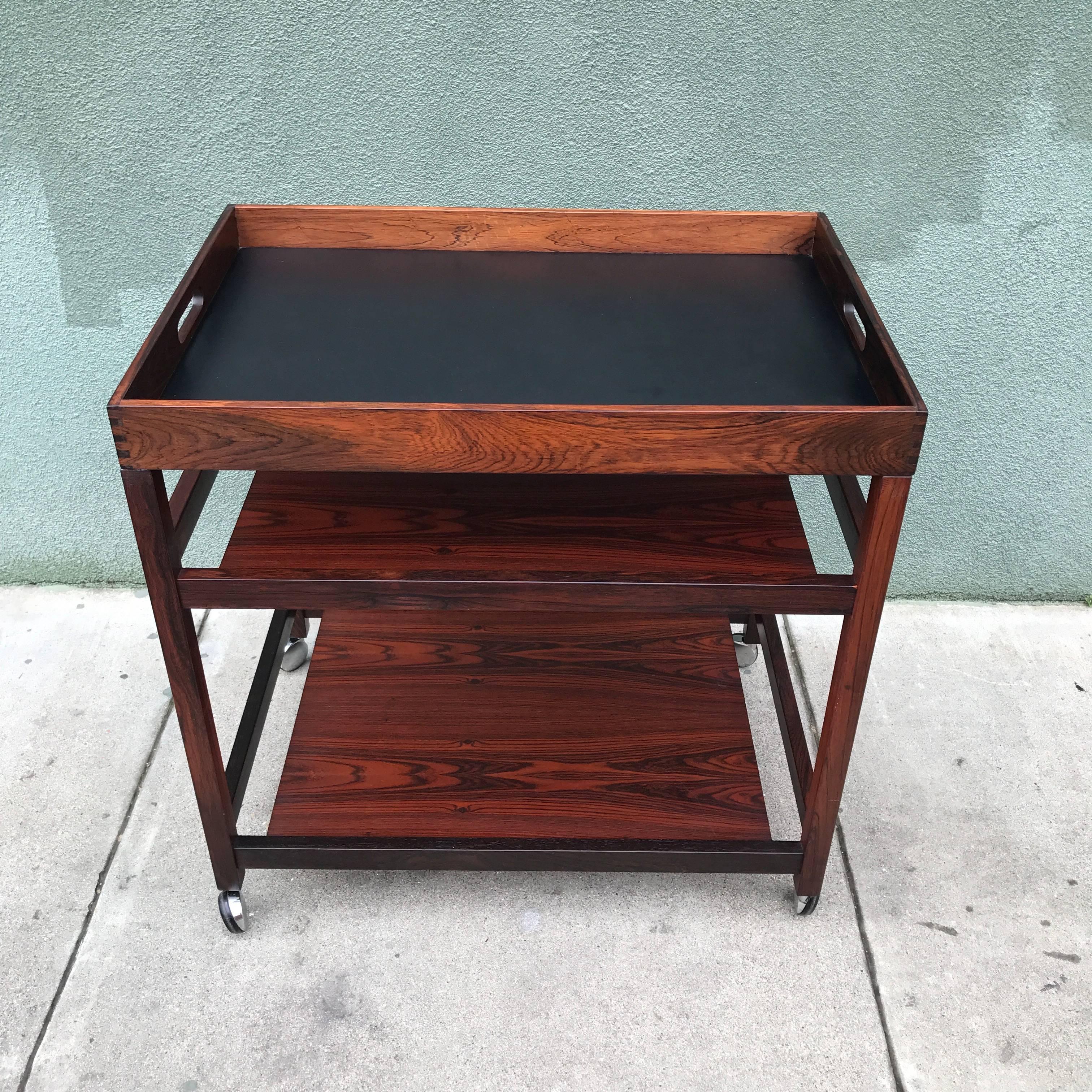 1960s Danish Modern rosewood bar or serving cart with a removable serving tray with black and red laminate surfaces and finger joinery. Very figurative rosewood grain throughout with an outstanding level of design and construction details, the two