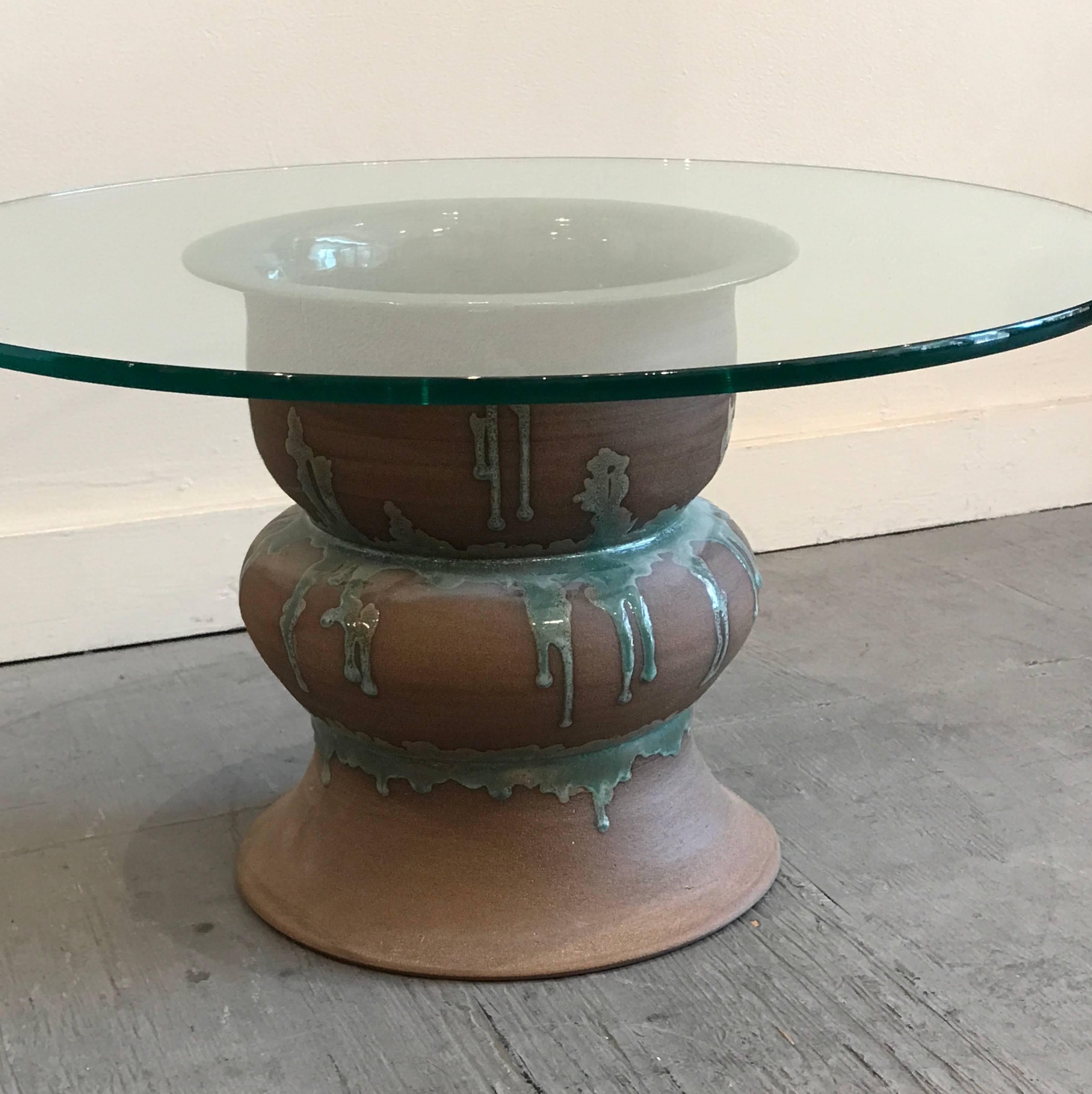 Hand thrown and glazed ceramic base side table with a round glass top. The ceramic base is a unglazed medium brown clay with sea green drip glaze accents to the side and is glazed in the interior of the piece. The base consists of two reversed