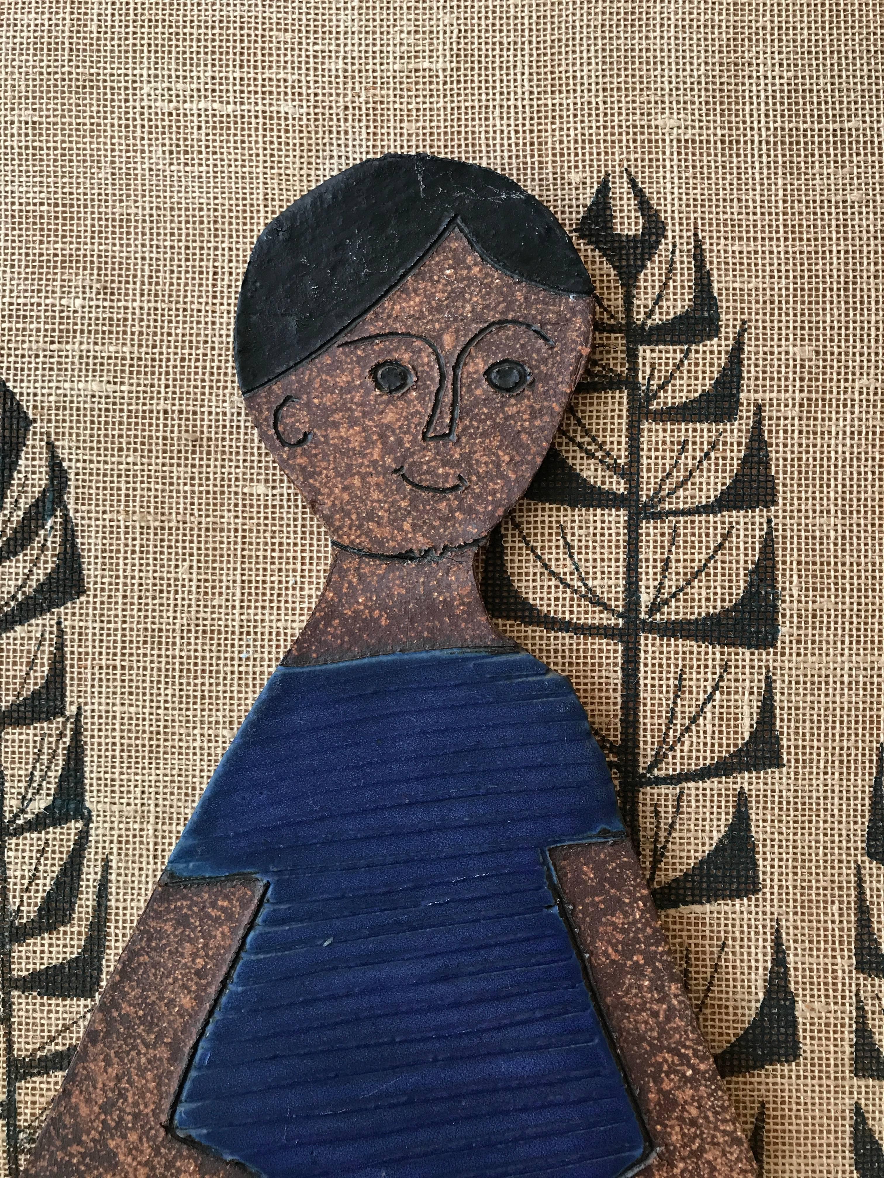 Ceramic figural wall hanging with a silkscreened burlap background by Southern California ceramic artist Raul Coronel. Coronel is known for his amazing range in the ceramic arts, from vessels, furniture and custom large-scale installations in both