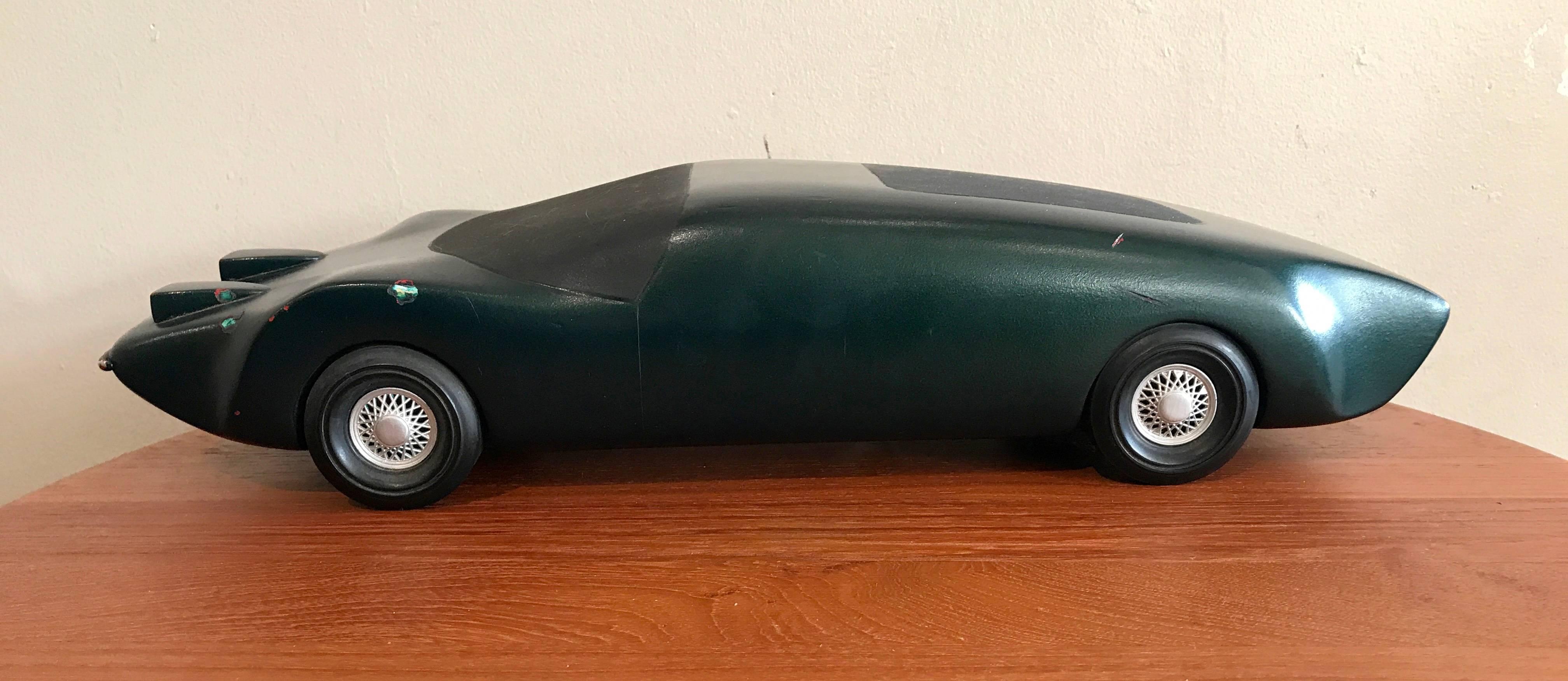 Wooden model car prototype said to be by a General Motors design works employee from the 1970s and then giving to design school students for inspiration. Solid wooden body painted green with rubber wheels. Wear to the surfaces from use as a design