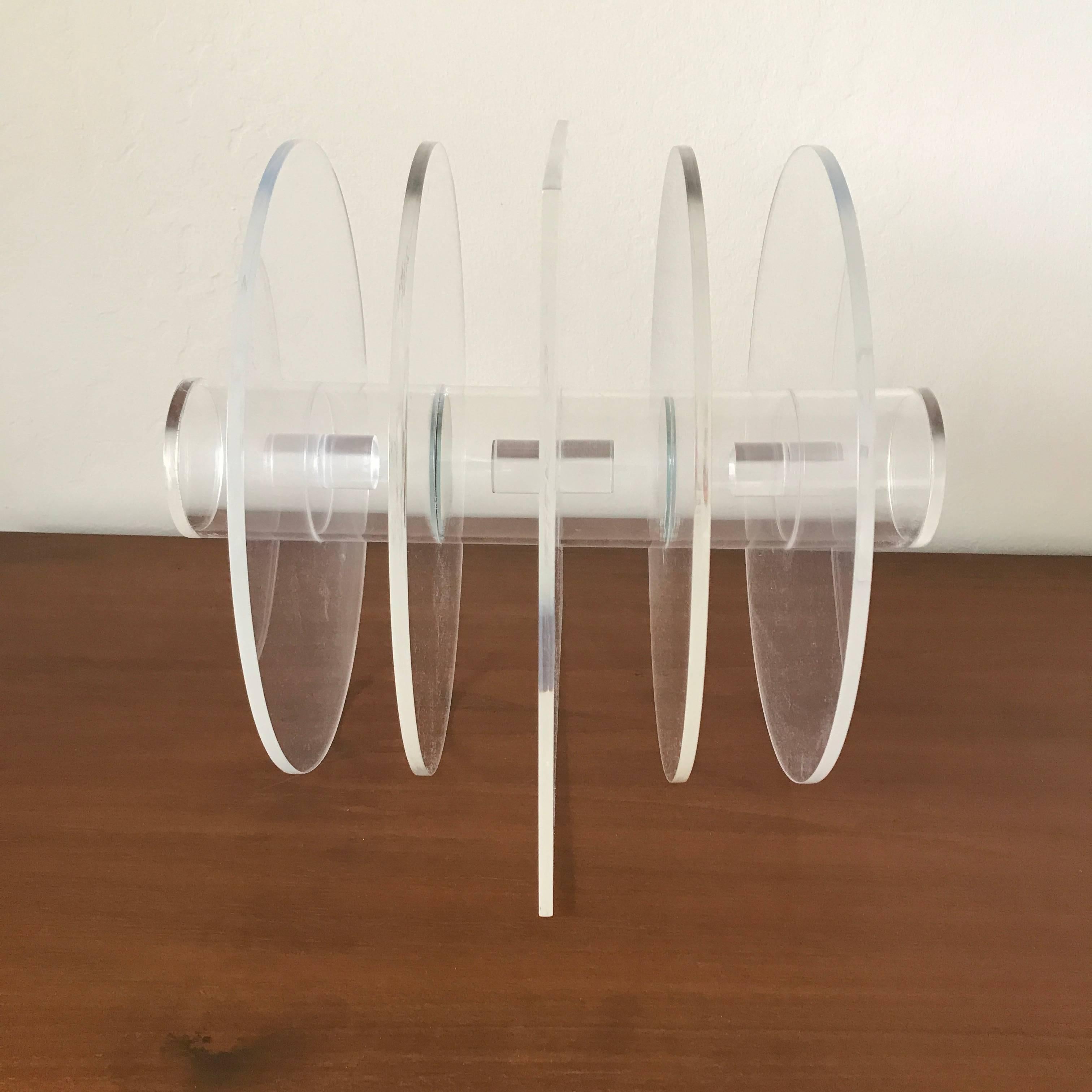 Clear acrylic hardedge sculpture by San Diego artist Bob Matheny (1929- ), consisting of circular forms and a square form in the center bisected with circular column the is segmented in the middle. The forms create a different visual narrative