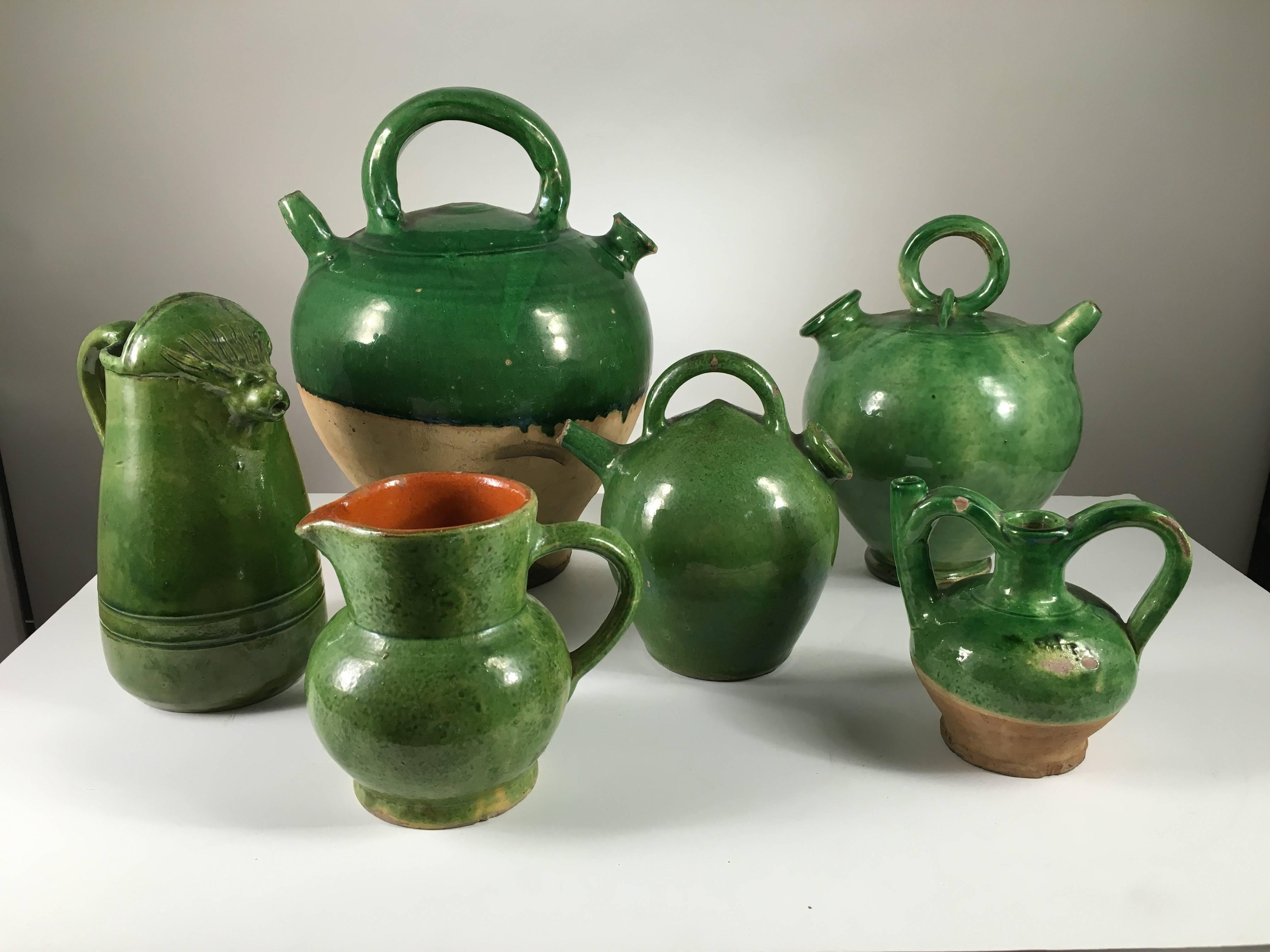 A collection of green glazed Provencale pottery from the estate of Pierre Moulin, author of French Country style books and founder of Pierre Deux, consisting of water jugs, oil jars, an interesting pitcher with a lion's face, and a casserole. 19th