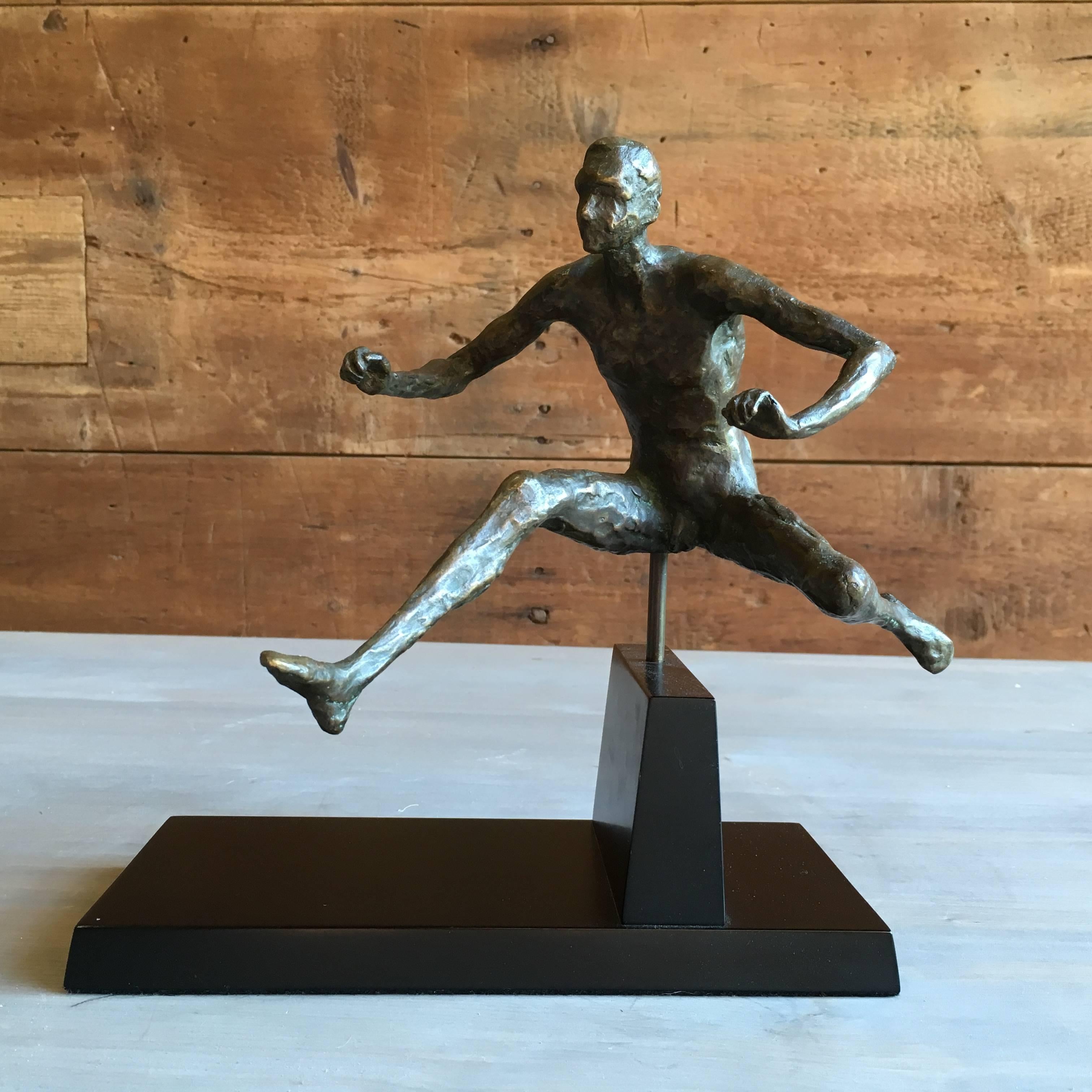 An unusual bronze statue of a male hurdler, on a wood base, 20th century.