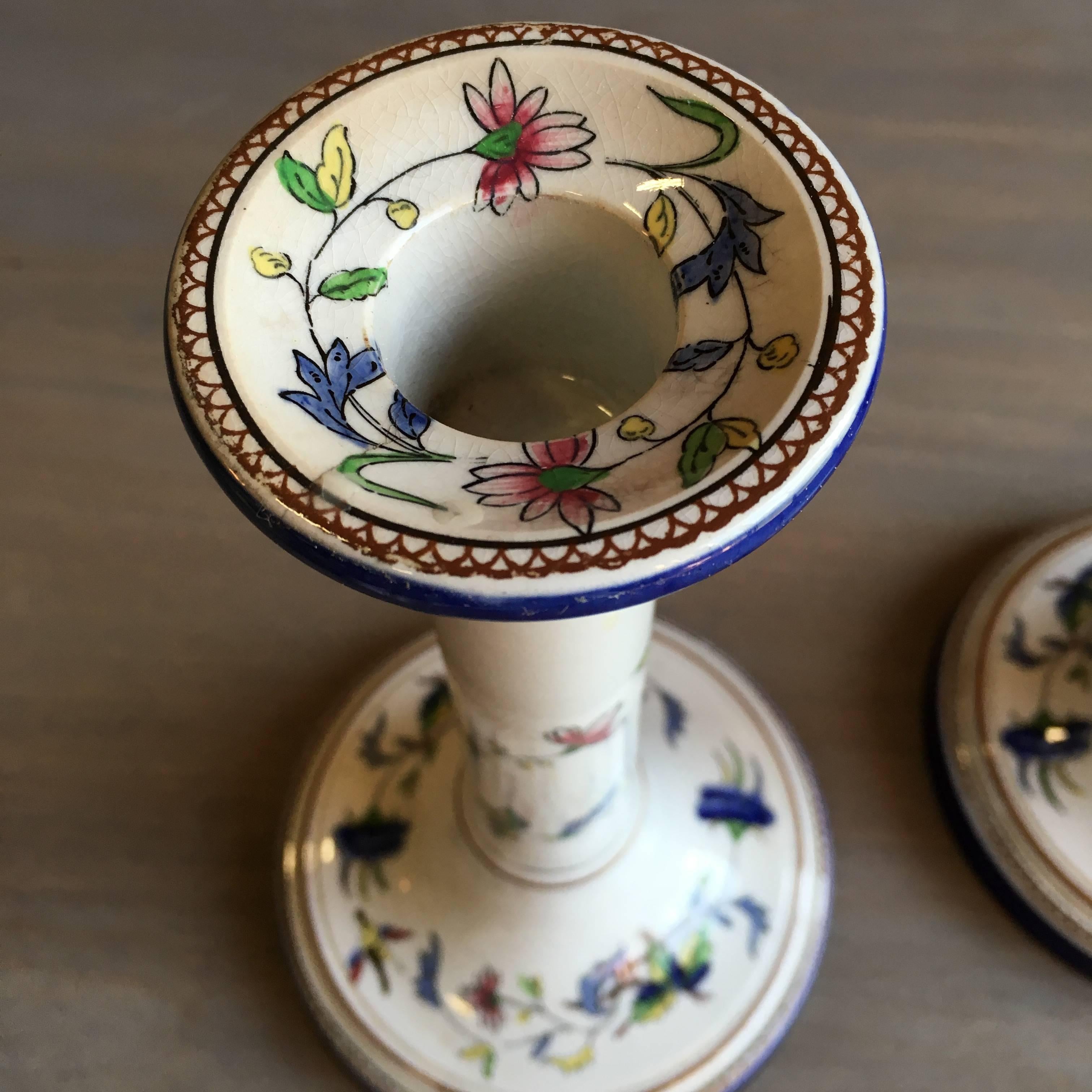 A pair of 19th century French faience candlesticks with floral decoration, signed on bottom, Rouen.