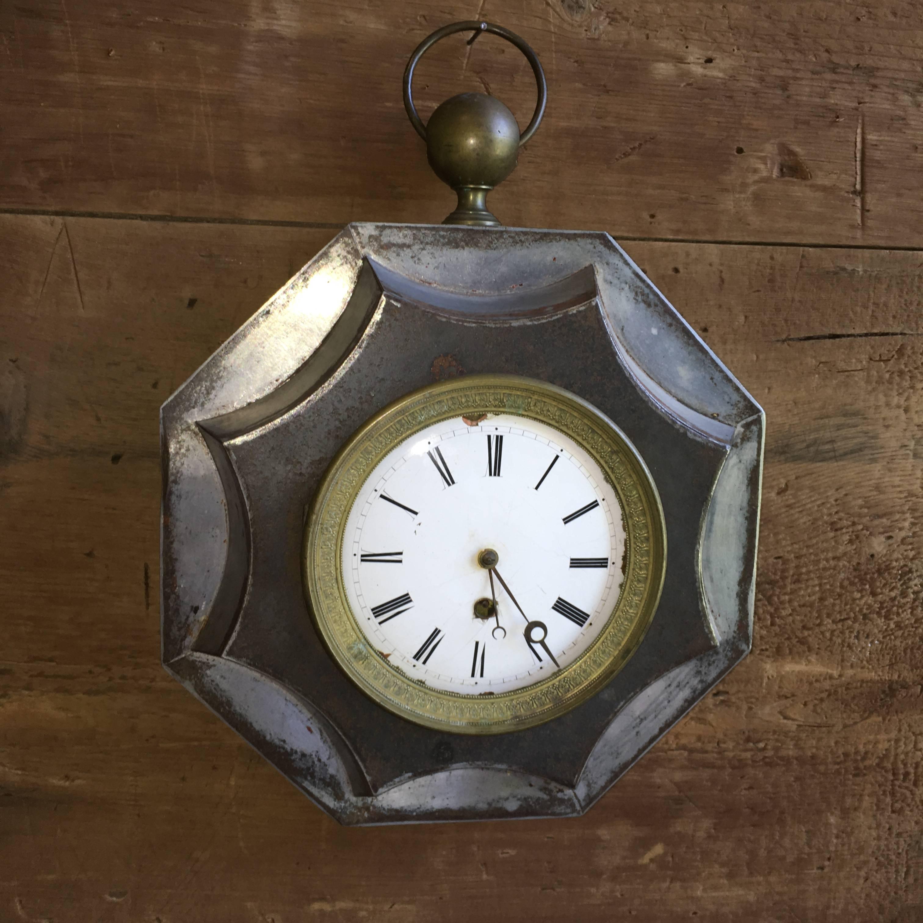 A decorative French Empire period wall clock in tole with brass details and porcelain face, circa 1810.