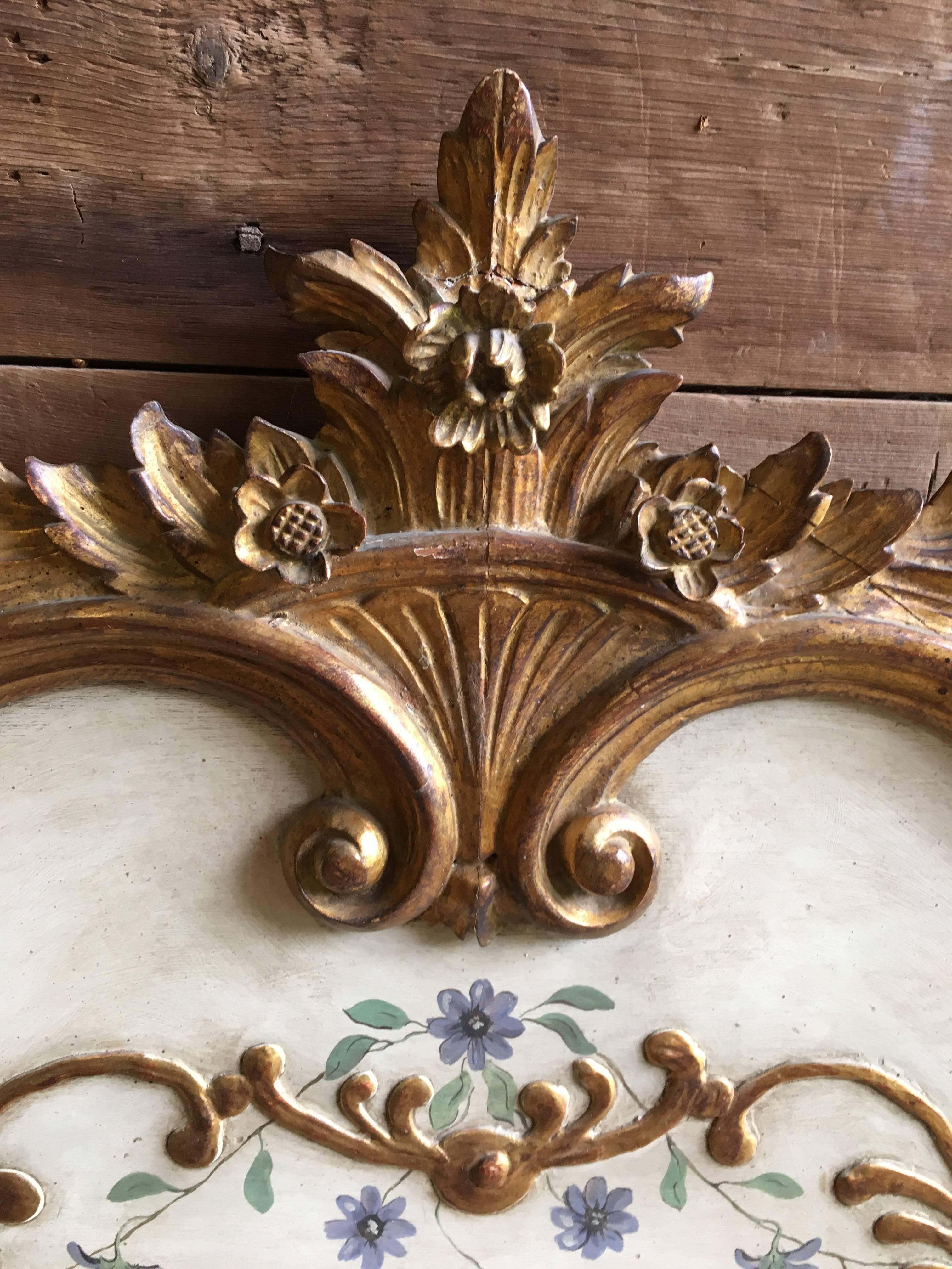 An elaborately carved and gilt Louis XV style headboard, king-size, with painted and gilt floral decoration, mid-late 20th century, Italian. The carved gilt-wood crest can be removed to allow for the headboard to be upholstered and the crest put