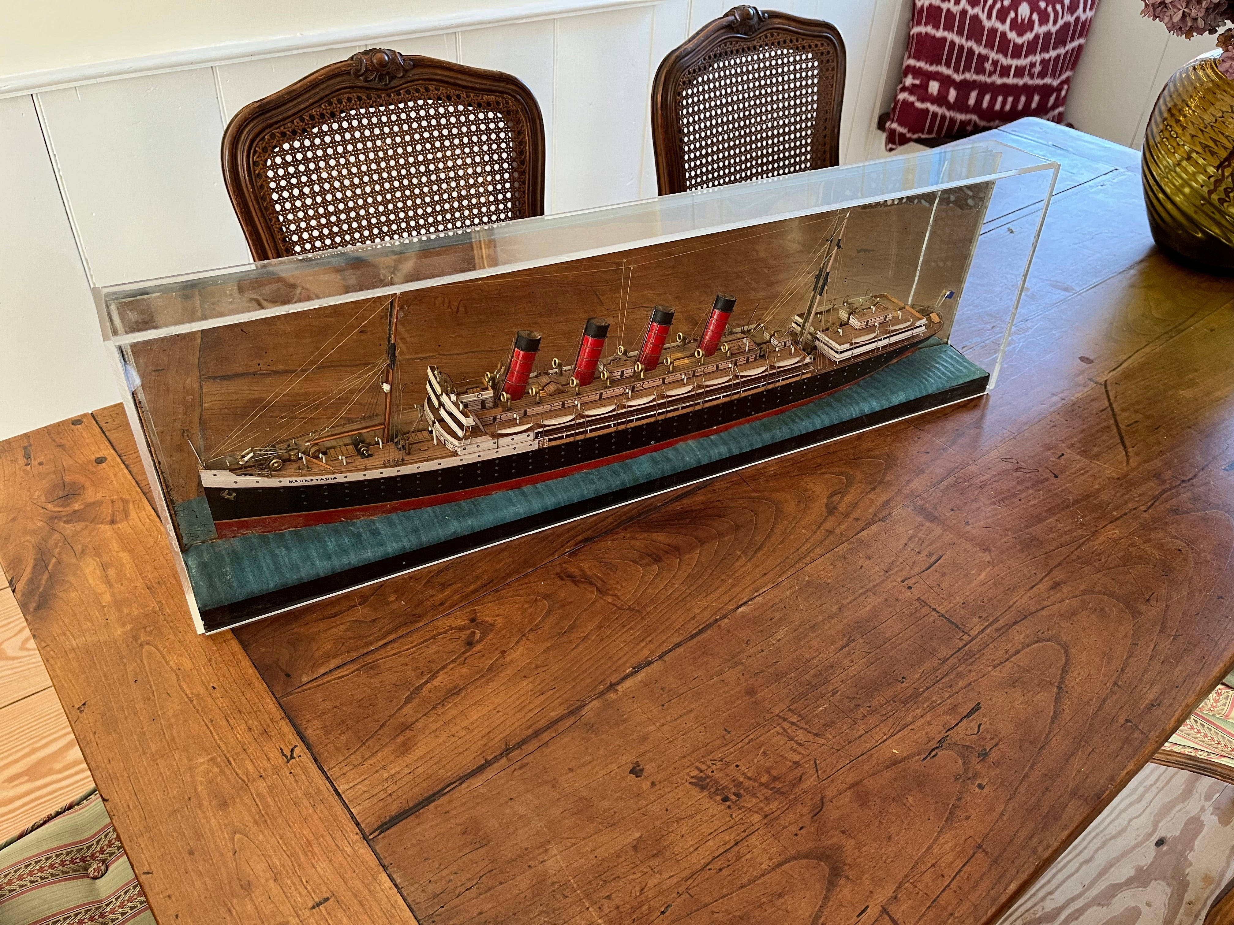 Belle maquette de demi-coque du RMS Mauretania, navire jumeau du malheureux Lusitania. Fabriquée à la main en bois avec des accessoires en métal, la maquette est astucieusement montée sur un miroir d'époque, ce qui donne l'illusion d'une maquette de
