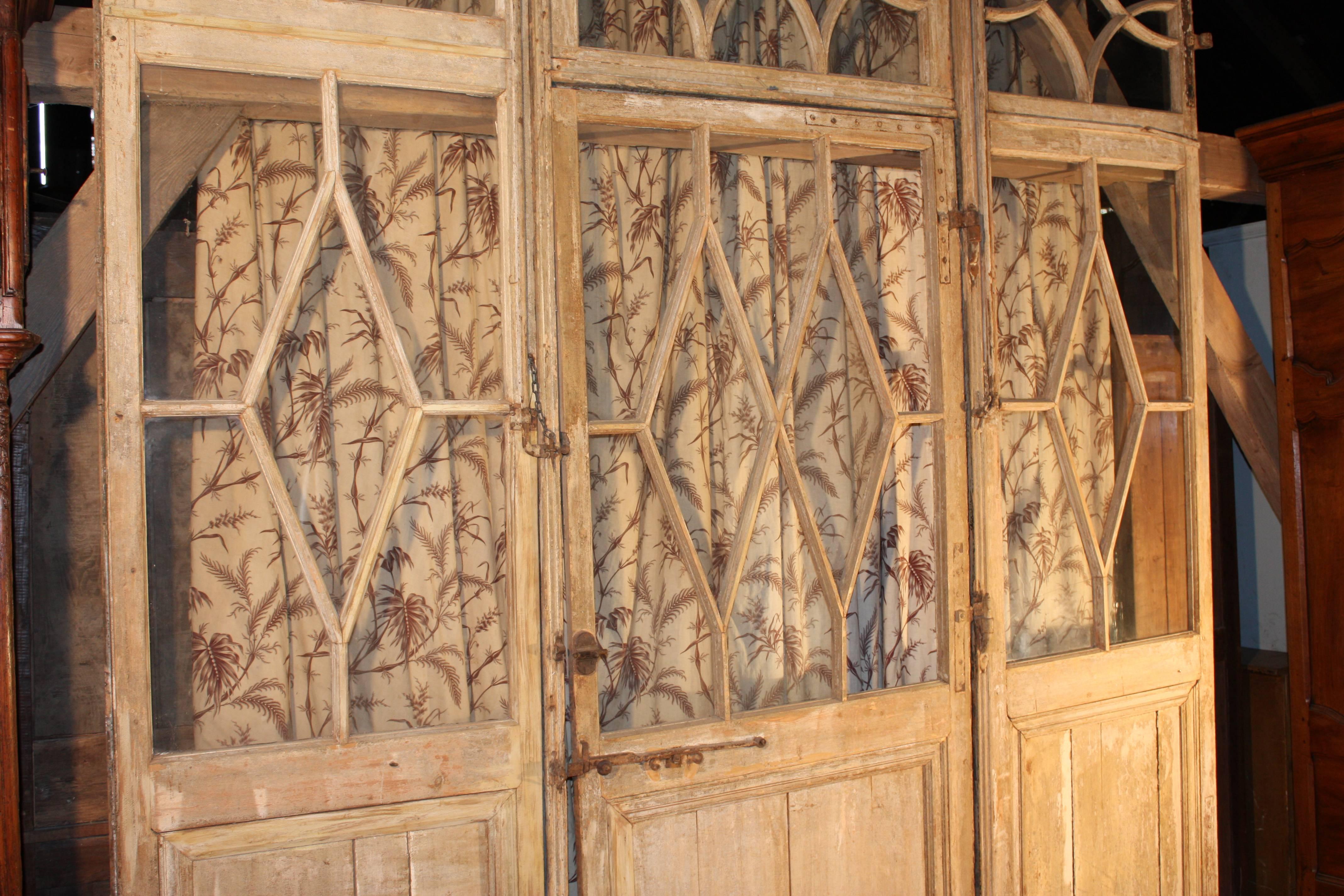 An early 19th century French paneled wall retaining its original cream painted finish and hardware with glazed upper areas. There is a center door and two side panels. This would be a great way to create a separate office area in a loft.