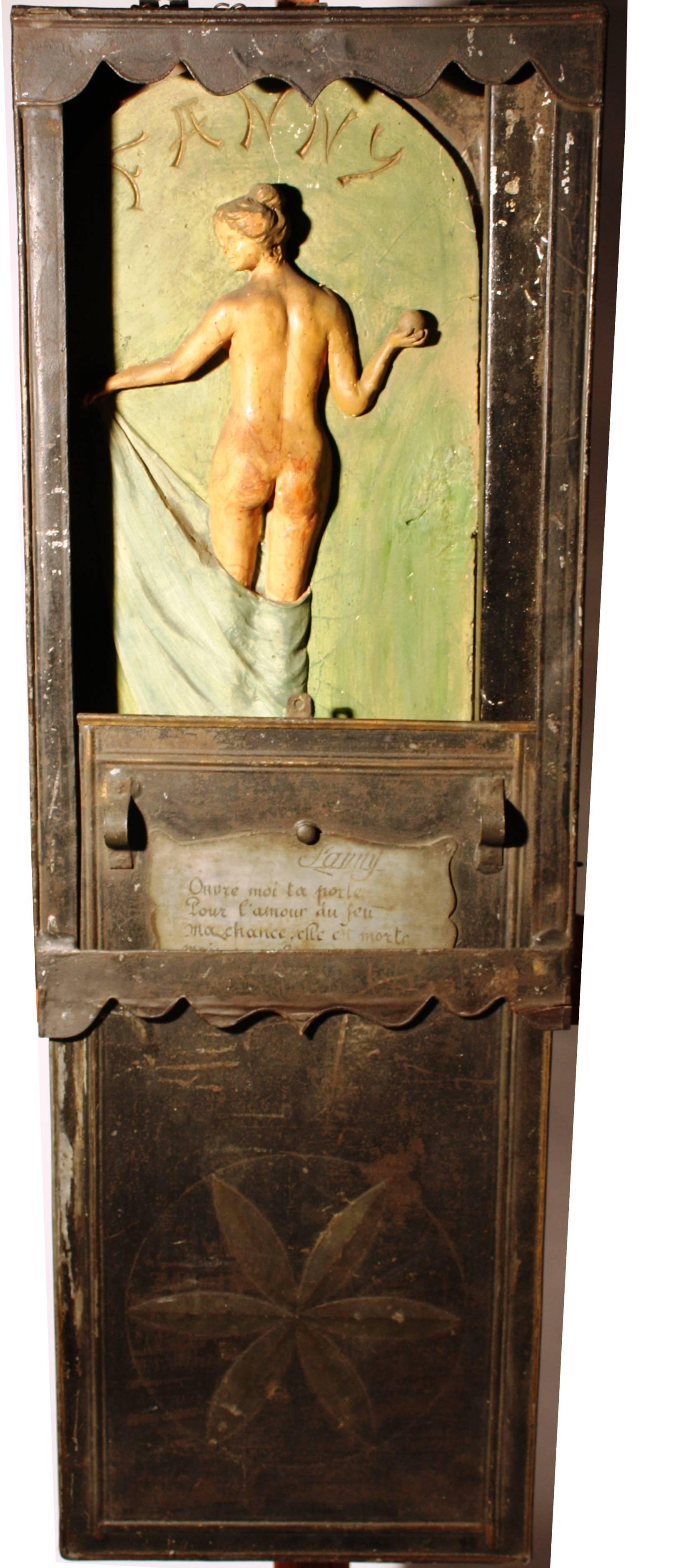 A rare 19th century Petanque (boule) "Fanny Box" from Provence, in tin with a painted composition figure behind a sliding panel. The front of the box has a metal plaque with a poem which can be loosely interpreted as "Open my door for