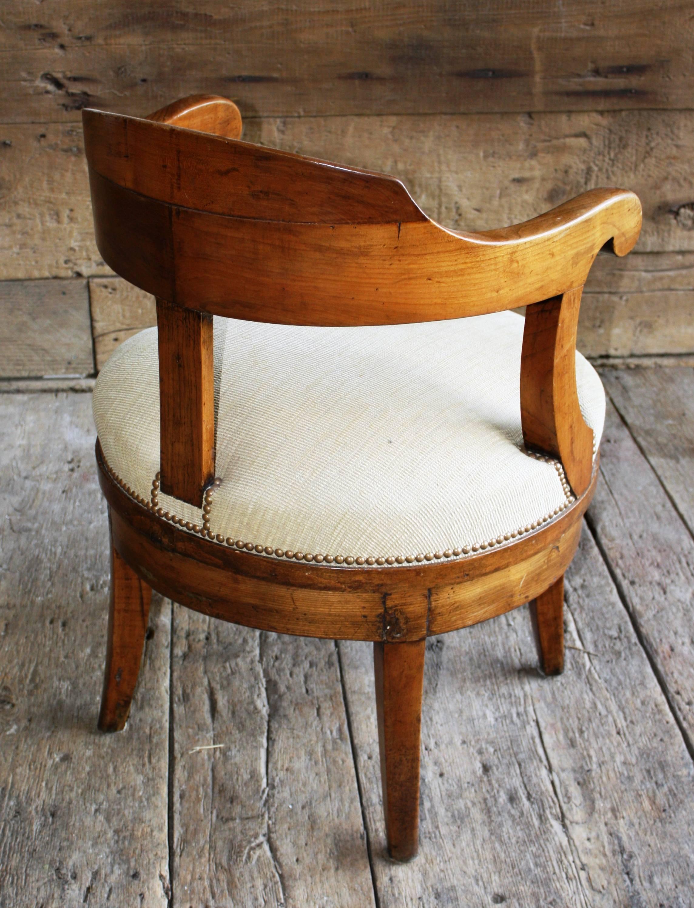 A nice French Empire period revolving desk chair, yoke-back design in cherrywood, circa 1810, newly upholstered.