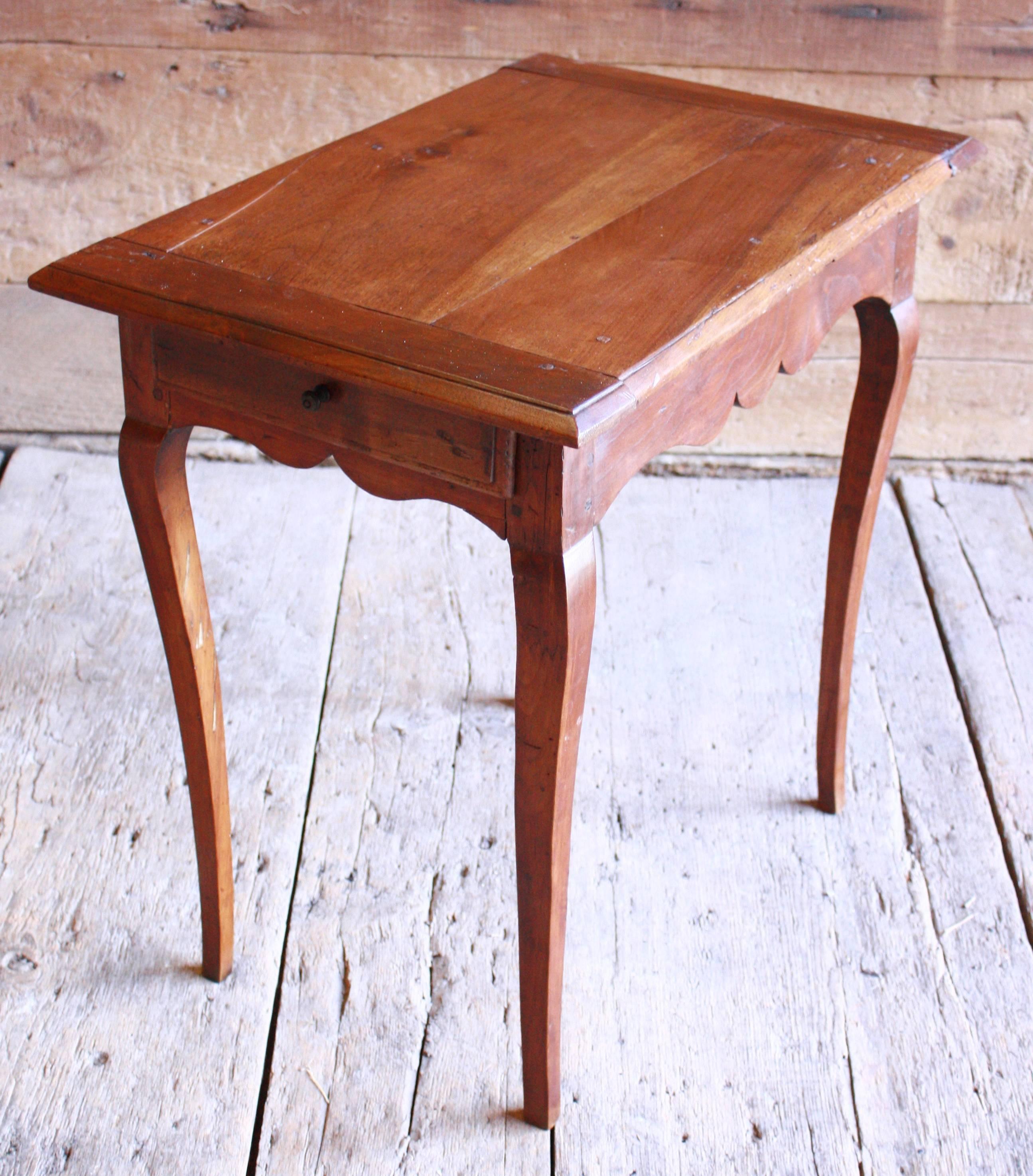 A provincial Louis XV side table in walnut, late 18th century French, with cabriolle legs, a scaloped apron and two small drawers.