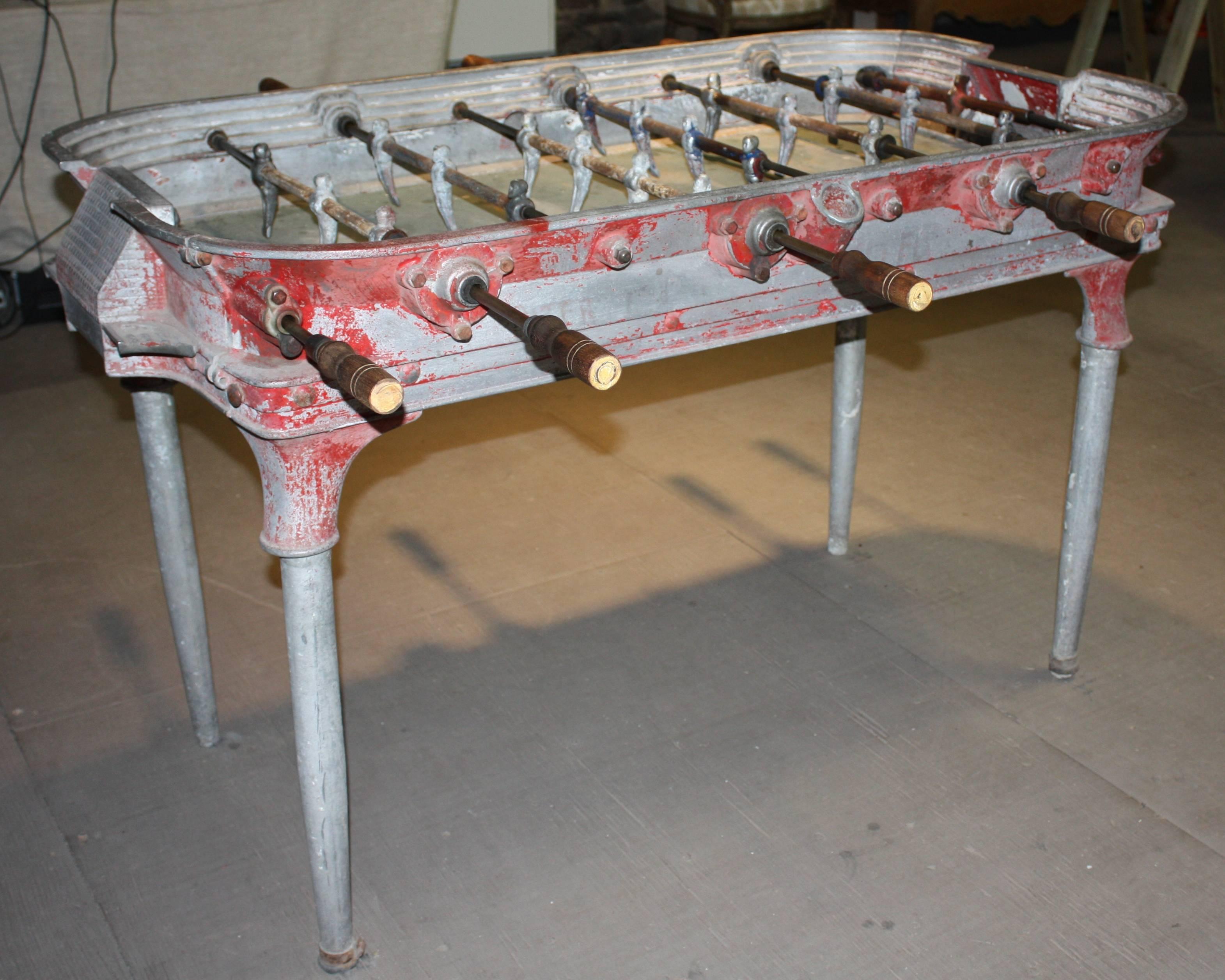 A well-worn cast aluminum foosball table "Estadio" from Buenos Aires, circa 1930, retaining some of its original red painted finish and green playing surface. This piece has great character -- "Steampunk" beat-up,