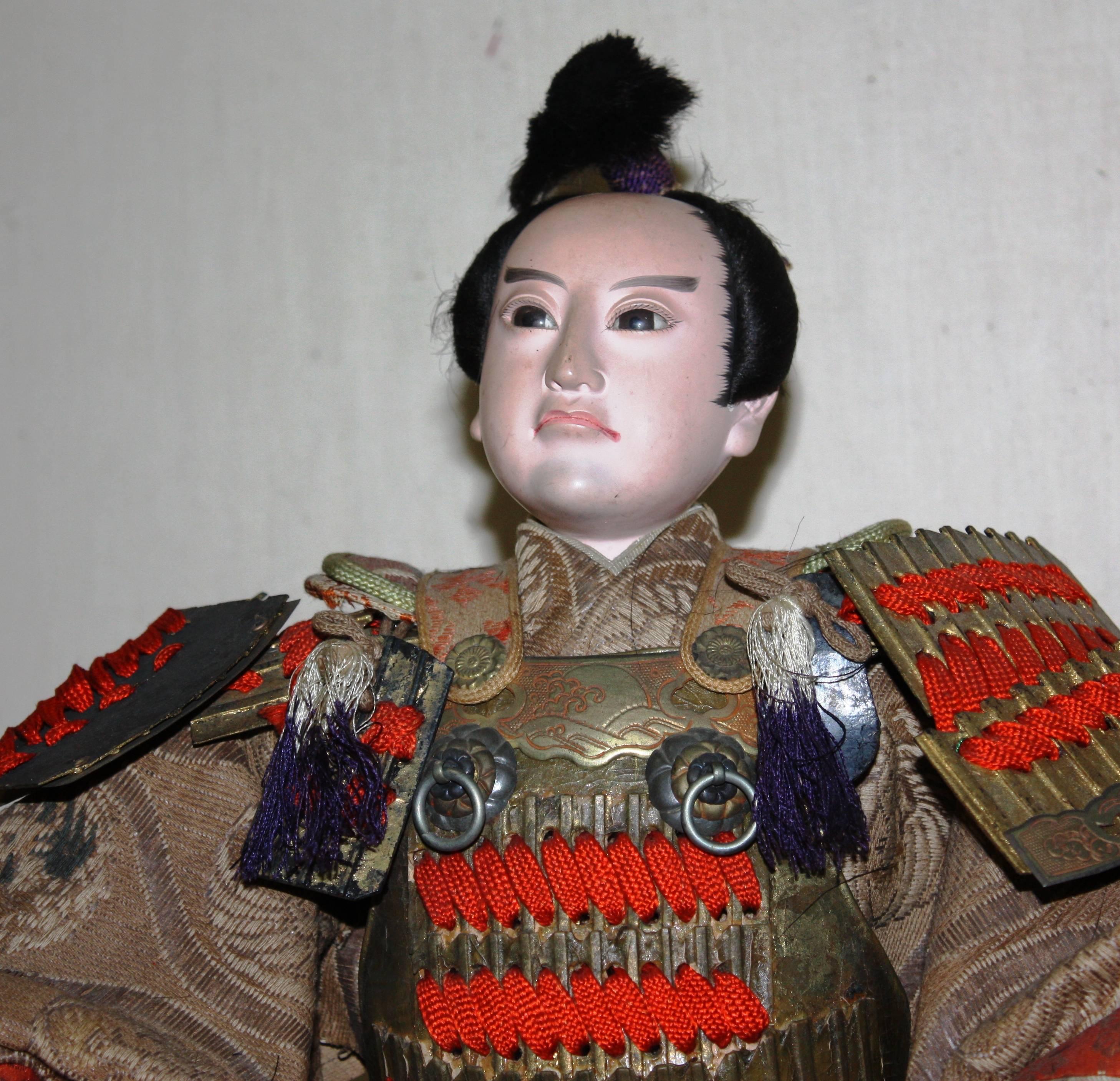 A Japanese samurai doll, Meiji period, late 19th century, with porcelain face and hands, with armor and period costume.