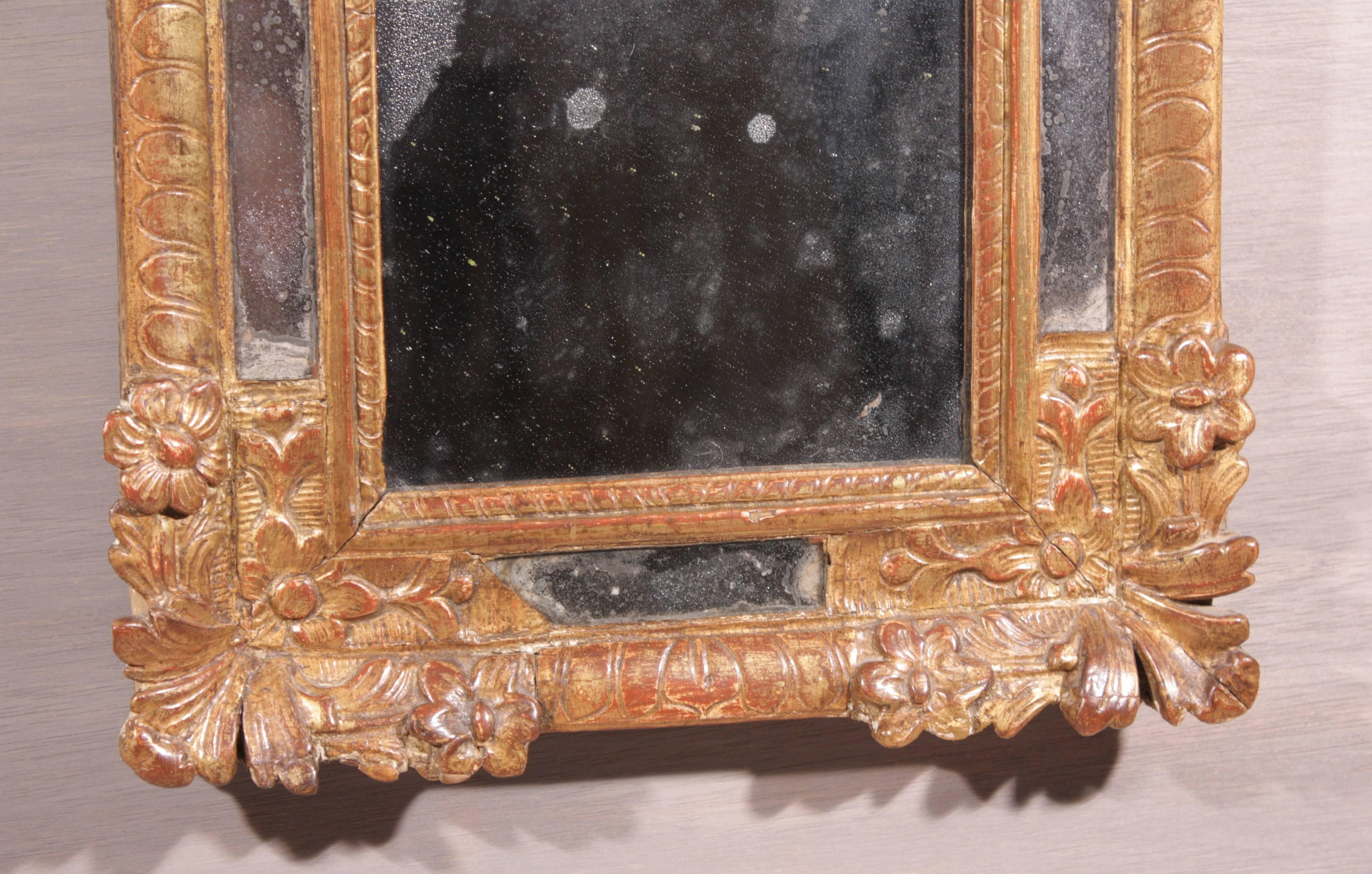 A petite French Regence period giltwood mirror, circa 1740, with original mercury glass plate.