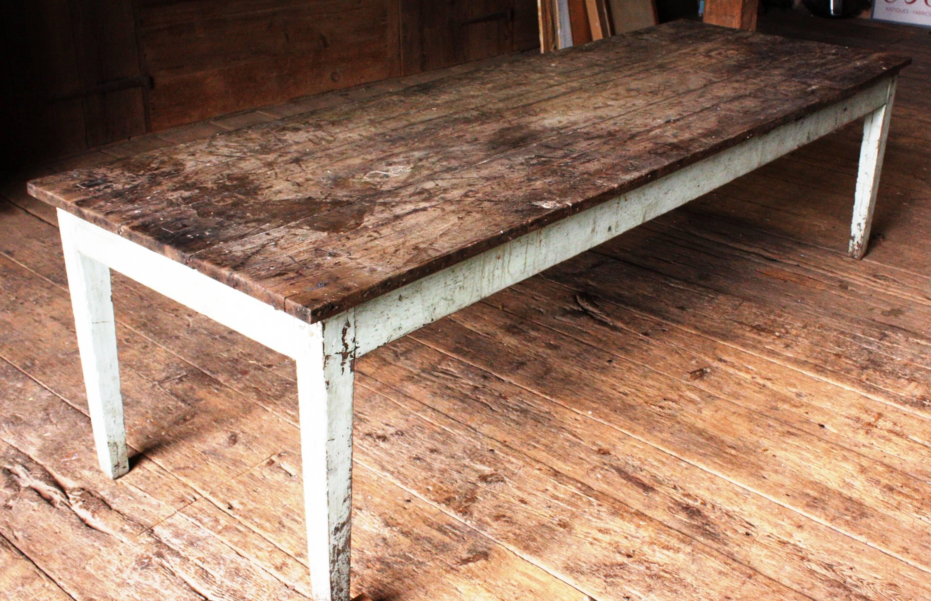 A 19th century French country plank top farm table with blue painted base, very distressed with wear and stains to the top. The underside of the table has interesting carved graffiti with dates ranging from the 1870s through the 1890s. 
Lots of