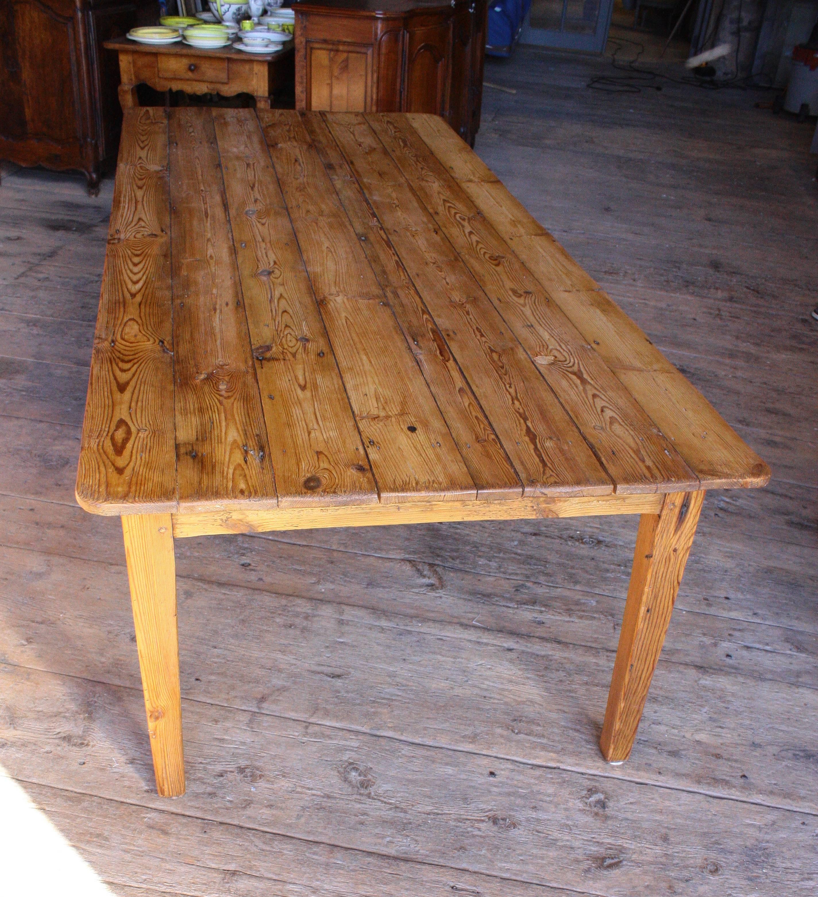A French country style pine farm table with tapered square legs and a simple apron.