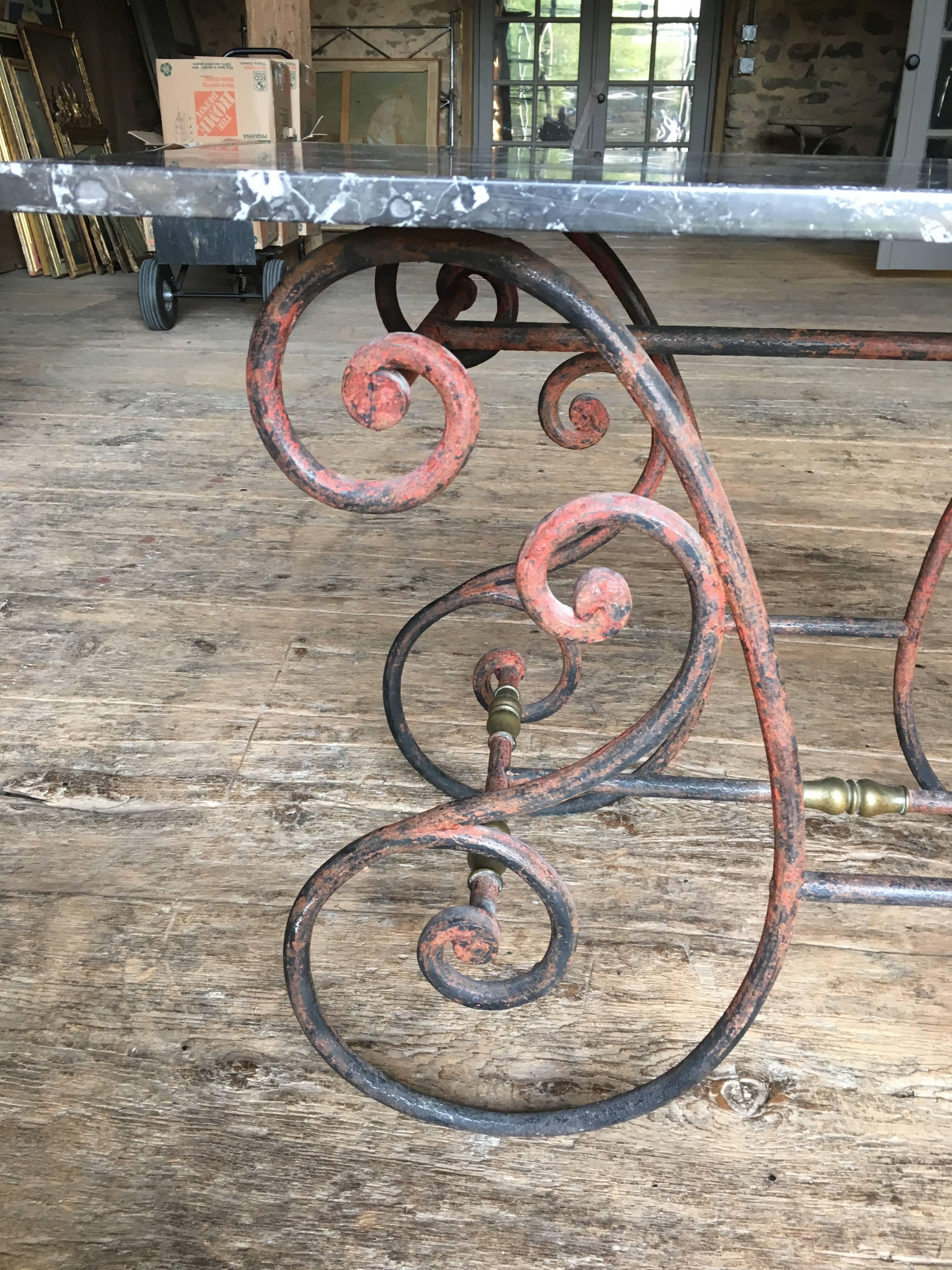 A nice French baker's table with grey marble top and a partially stripped wrought iron and brass base, showing areas of red painted finish, circa 1890.