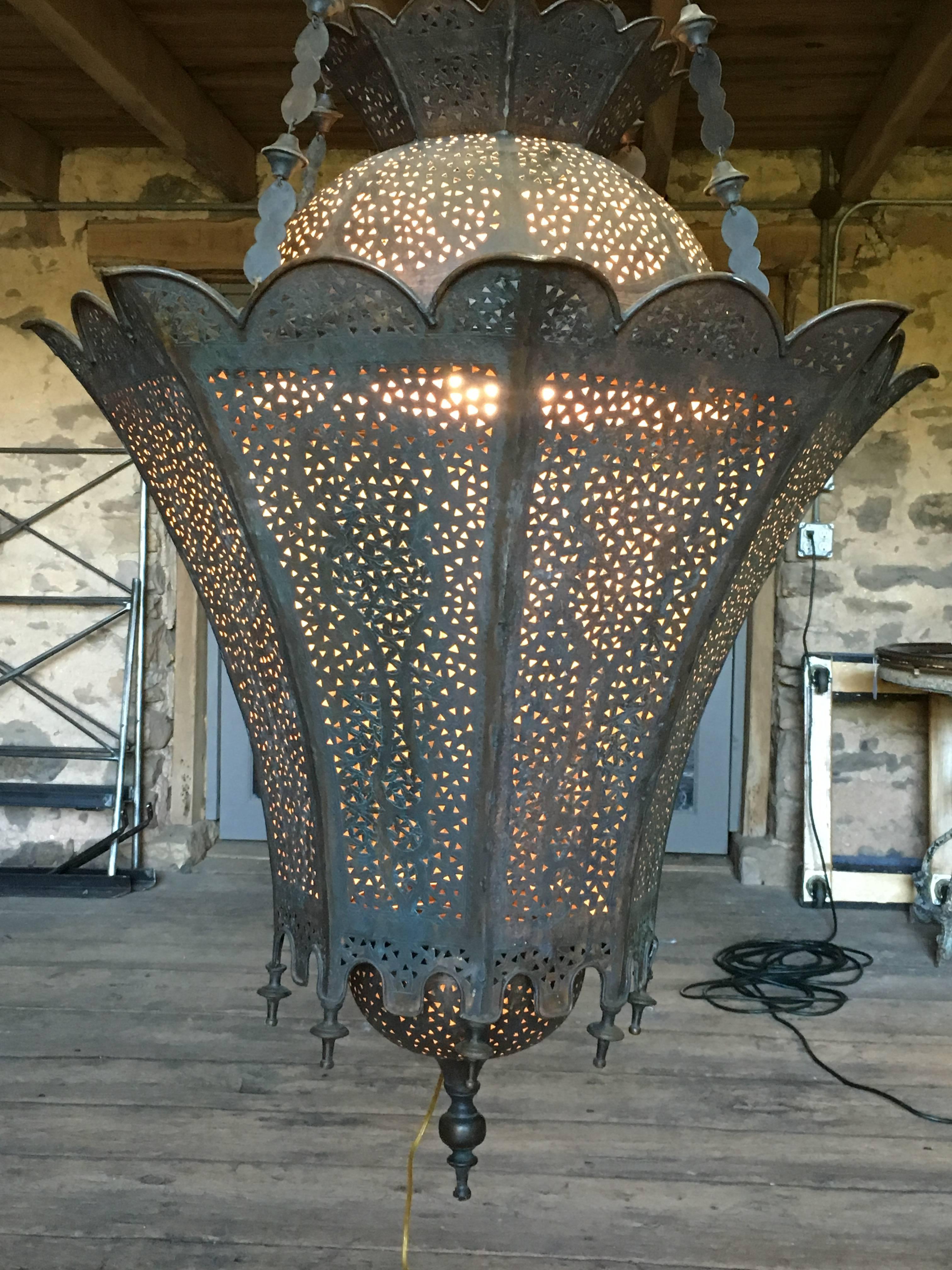 A wonderful over-scale lantern in pierced brass with turned finials, Moroccan, circa 1890. The lantern is illuminated by a single bulb inside. Height of lantern body is 42