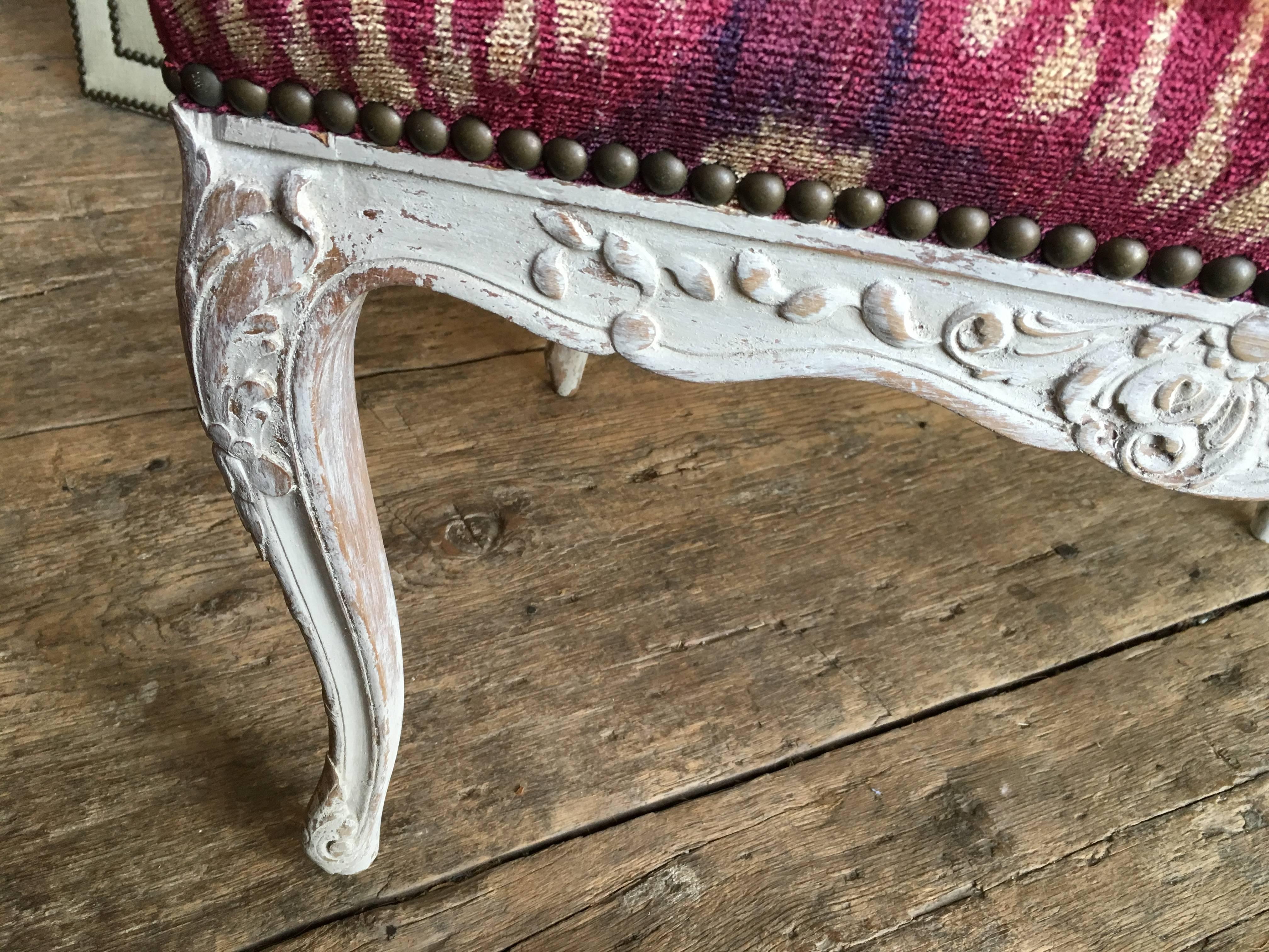 A Louis XV style carved and painted two-seat window bench, with cabriole legs and scalloped apron, late 19th century French, recently upholstered in burgundy handmade silk velvet. Great size for the foot of a bed.