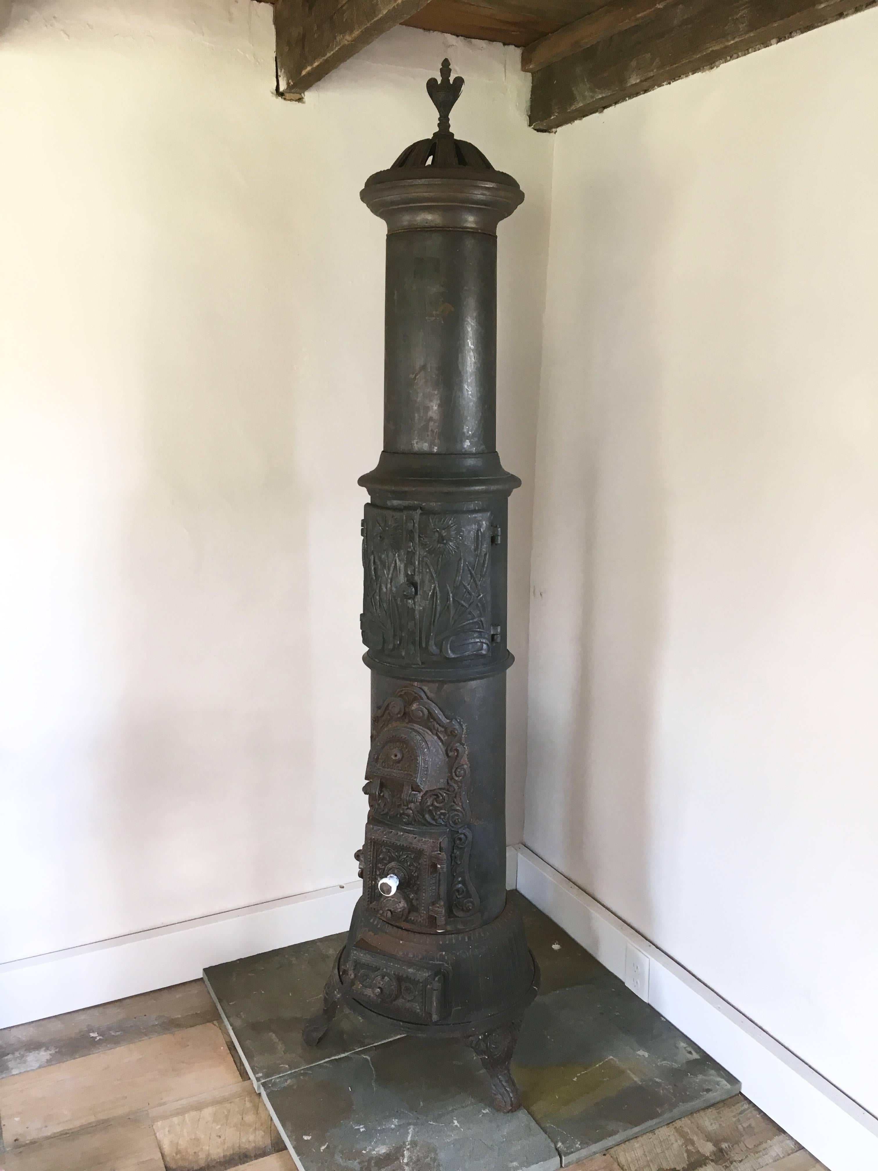 An unusual Swedish cast-iron parlour stove, circa 1850, with decorative embossing on several doors, a porcelain handle and a nice crown with finial on top. It appears to be functional with all parts present, but being sold as decorative since it has
