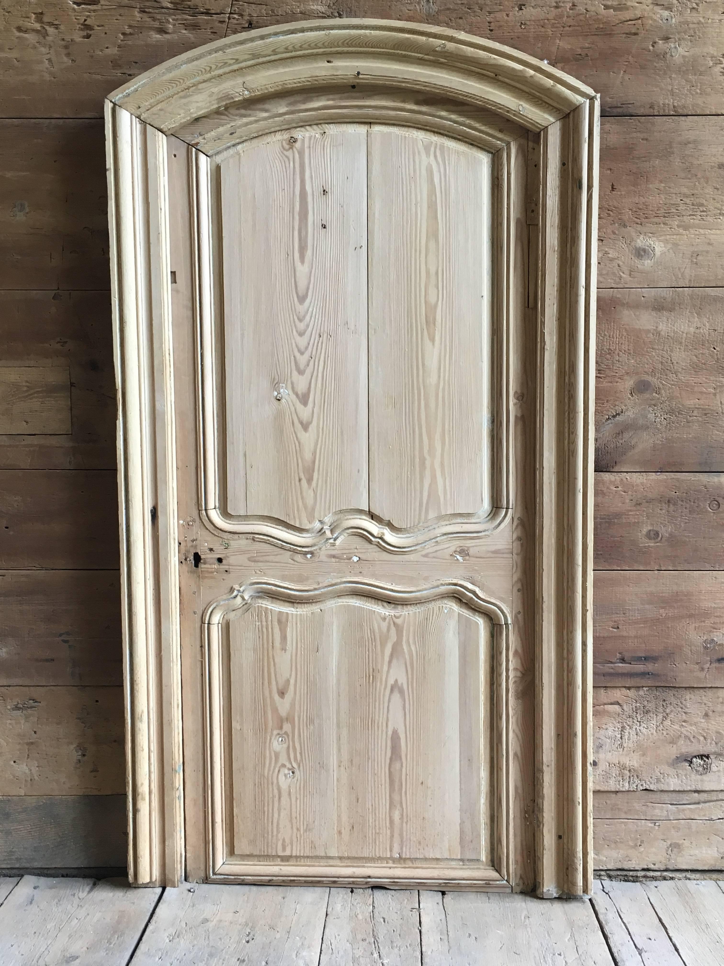 Une porte d'intérieur Louis XV dans un cadre avec panneau de sur-porte, en pin décapé et blanchi, vers 1760, de la région de Normandie. La porte conserve sa serrure d'époque montée en surface (sans bouton). Peut être utilisé avec ou sans panneau