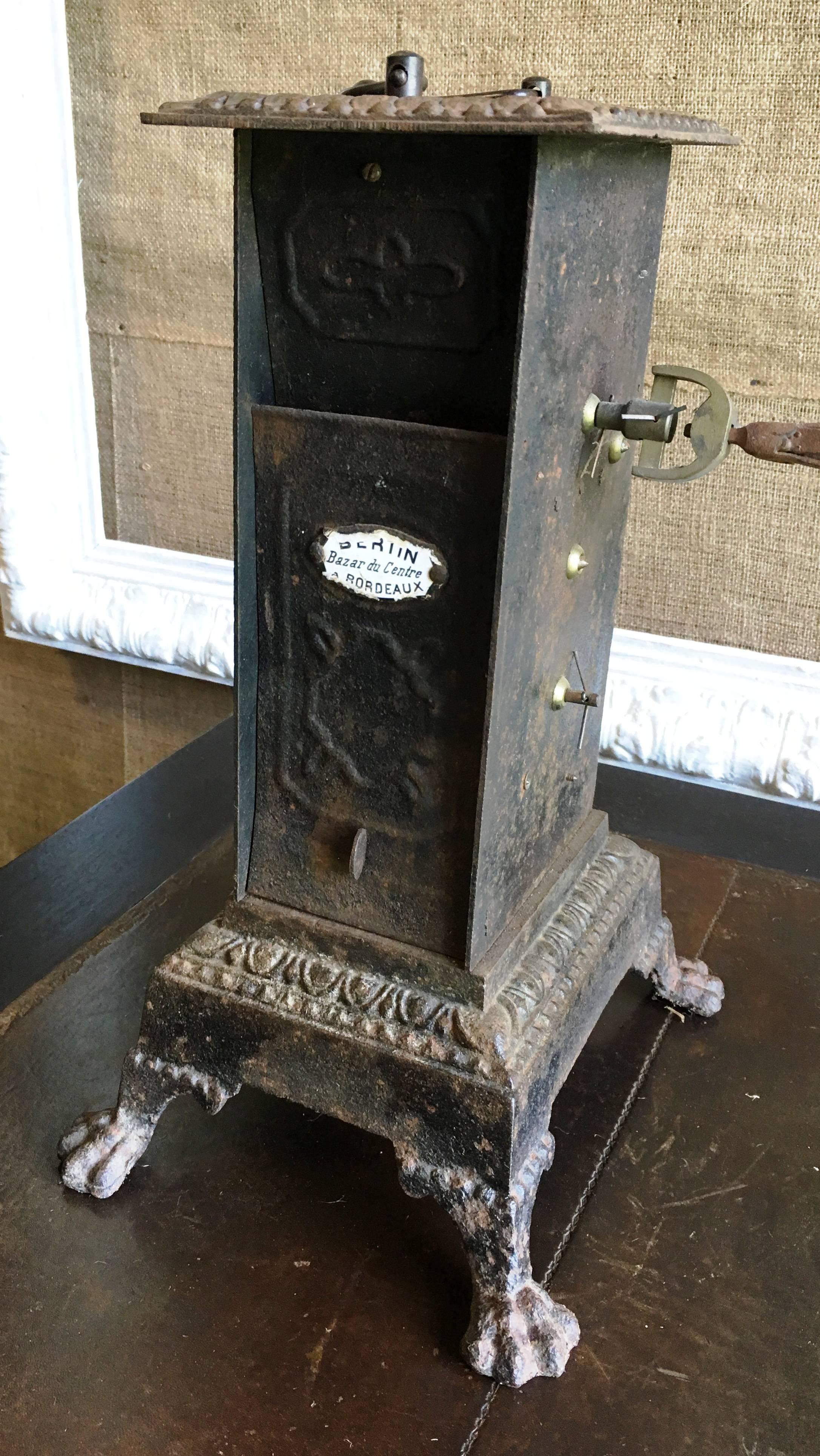 An unusual French Mechanical Rotisserie, circa 1870, with wind-up clock mechanism. These were placed in front of a fireplace in order to cook meats and poultry. A long pan was often placed beneath to collect the drippings. The cast iron housing is
