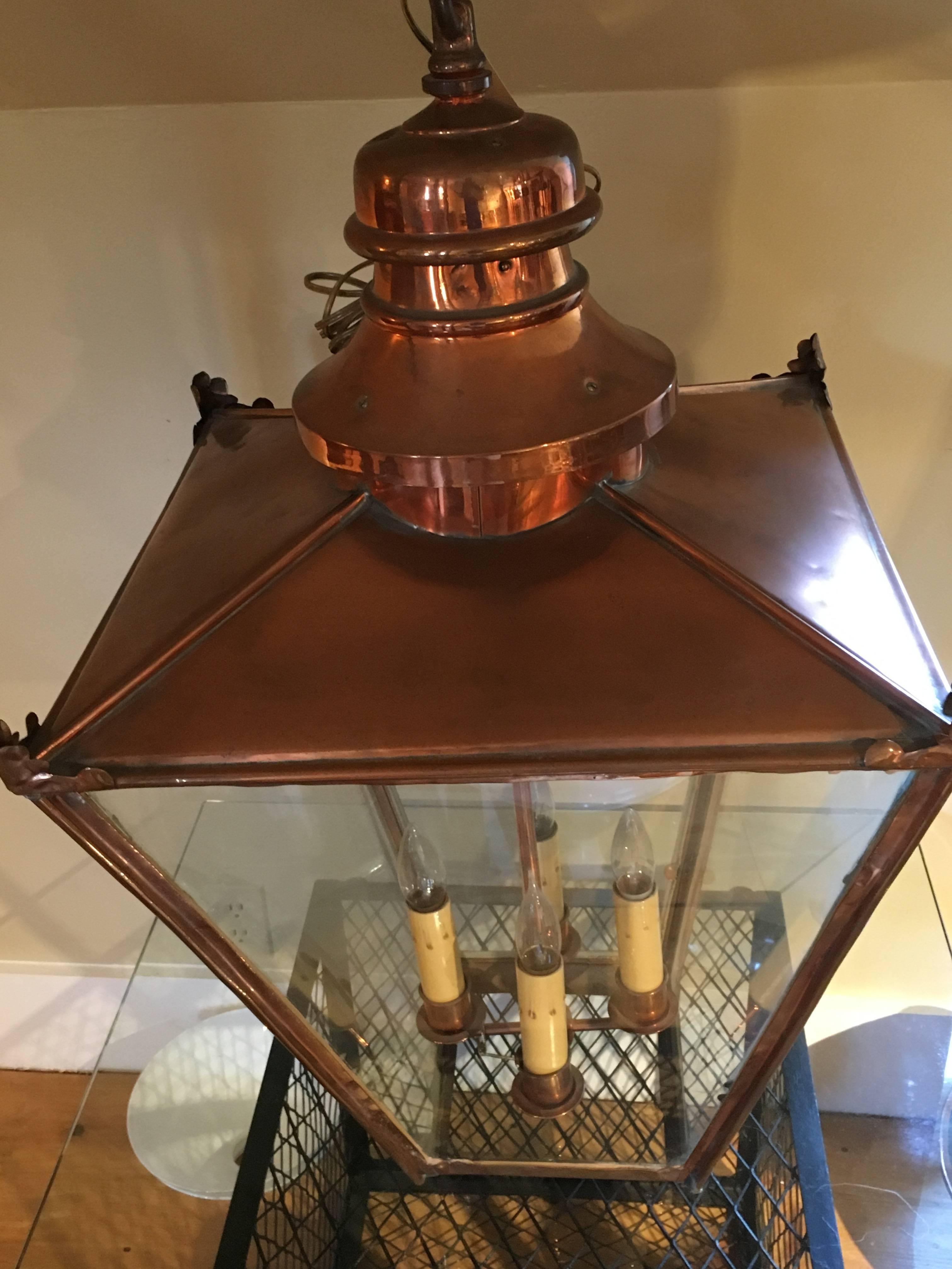 A large Georgian style English hanging hall lantern in copper with glass panes, a chimney top and a four-light cluster with candelabra bulbs.