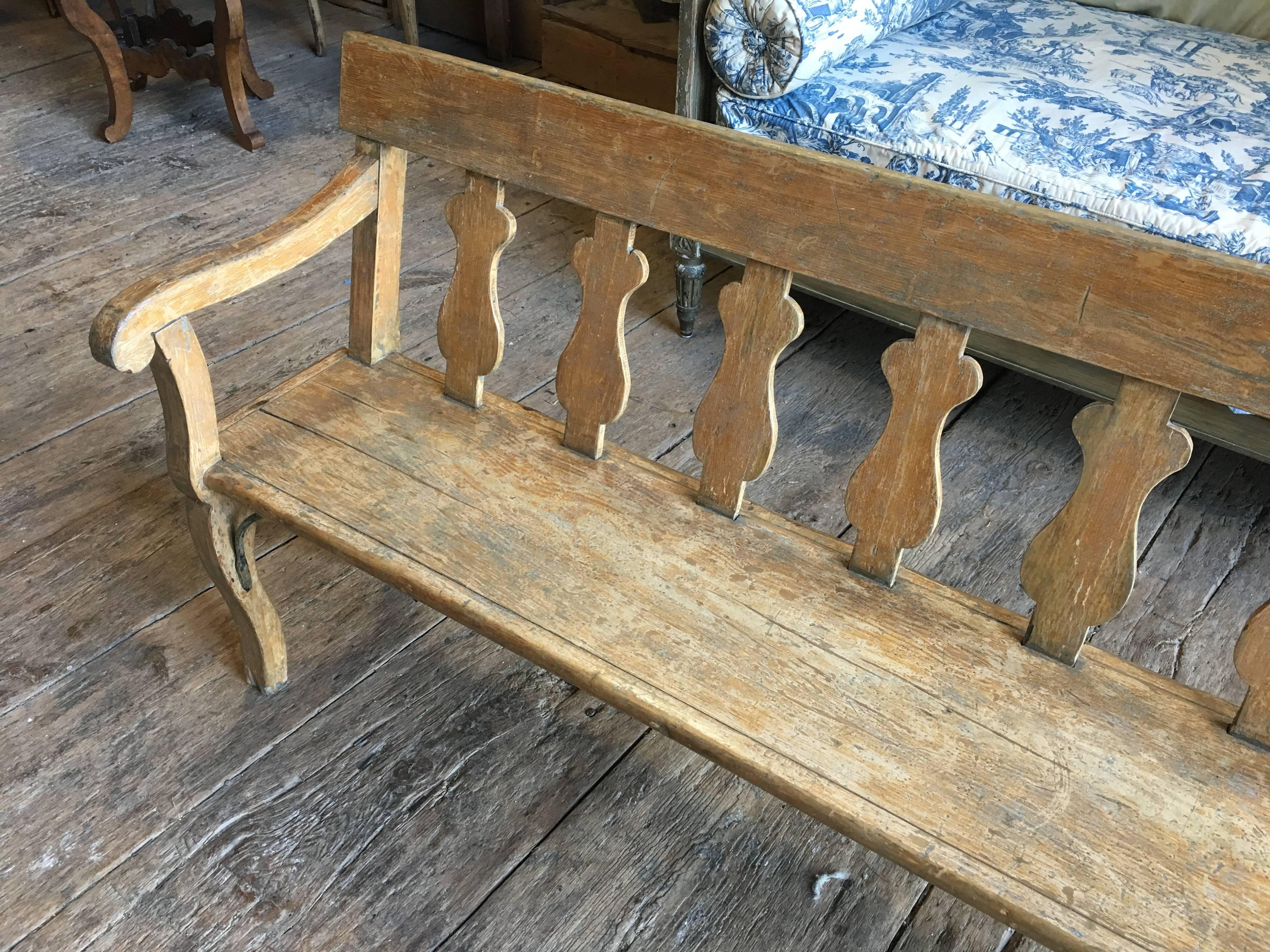 A 19th century French hall bench with scroll arms and a back with urn-form panels, retaining its original faux bois painted finish. Very sturdy. Great at the foot of a king size bed.