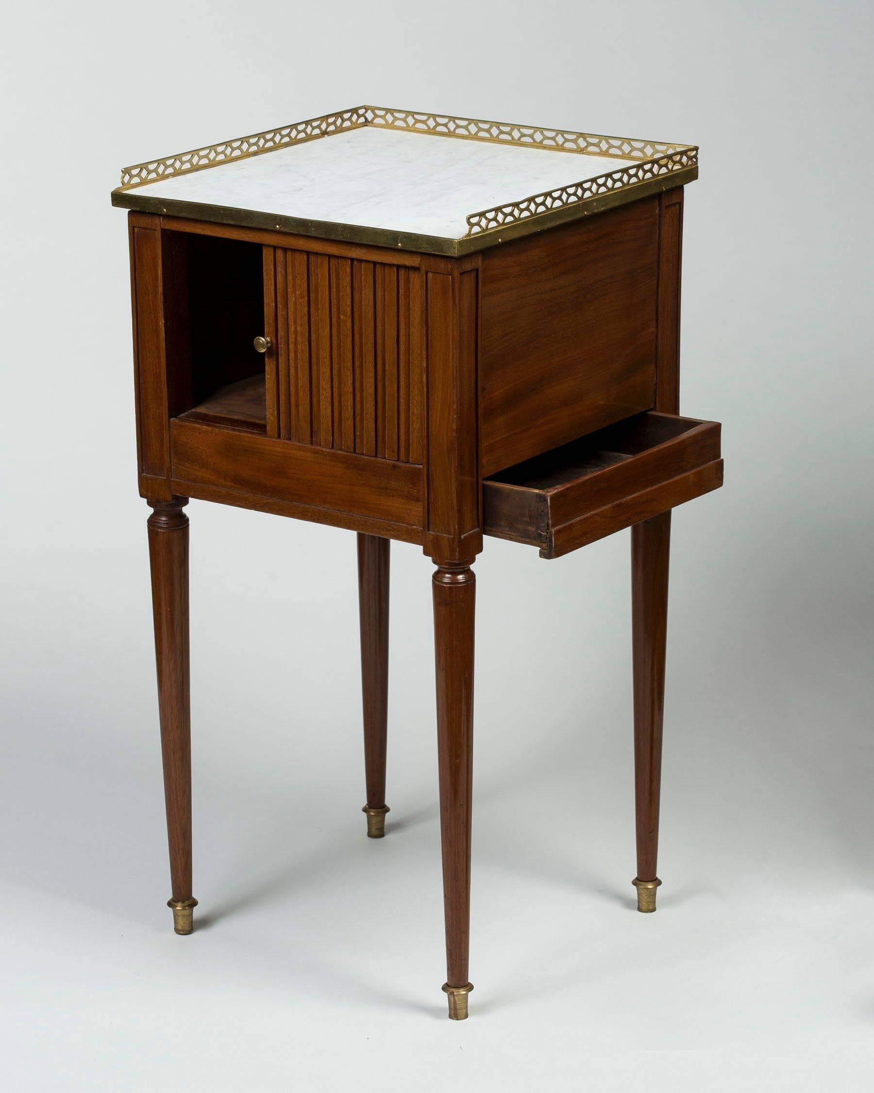 The square veined white marble-top and brass gallery above a tambour door and a side drawer, the turned tapering legs terminating in brass caps.