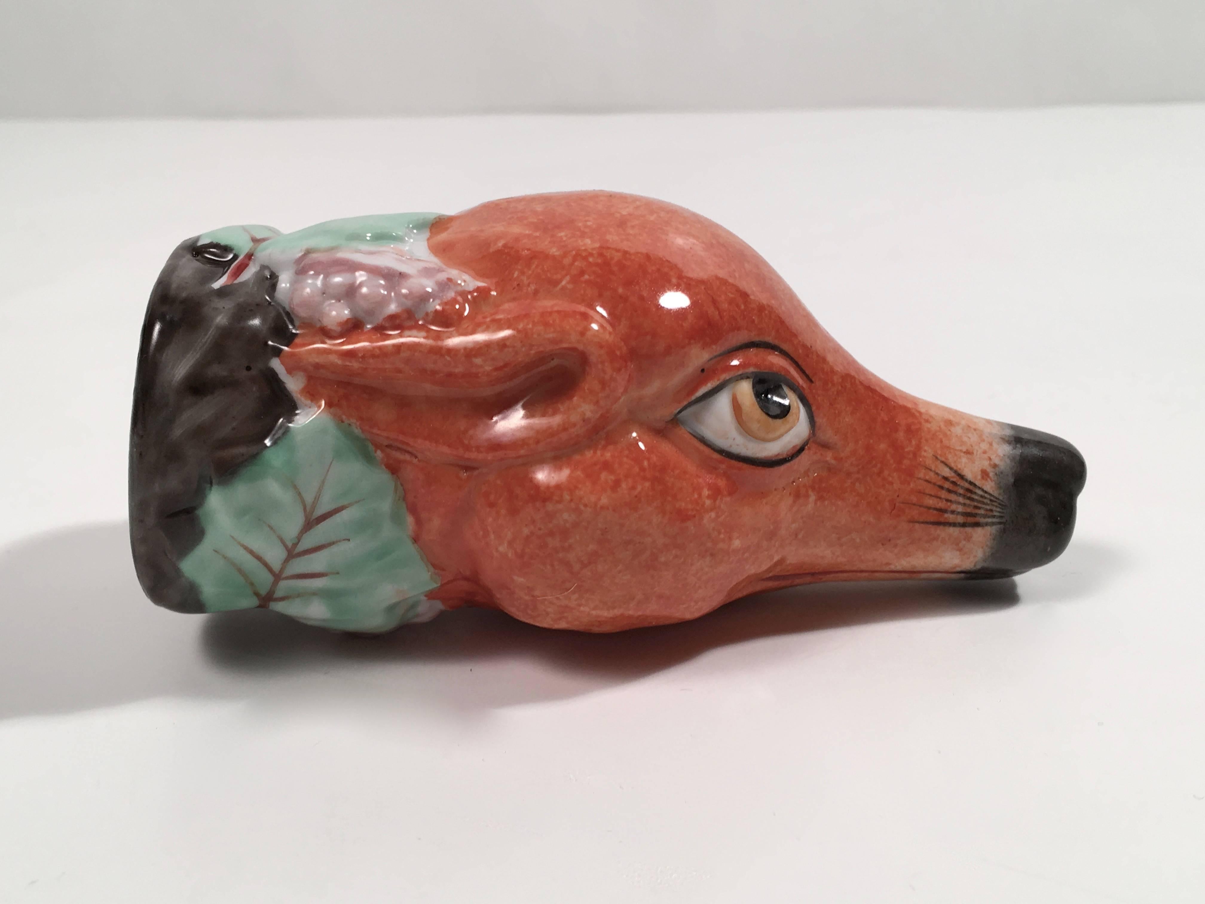 A Staffordshire fox head form stirrup cup, the molded and glazed pottery vessel with expressive fox head, its neck festooned with grapes and grape leaves, English, circa 1810-1820. 
Stirrup cups were drinking cups and are so called because wine and