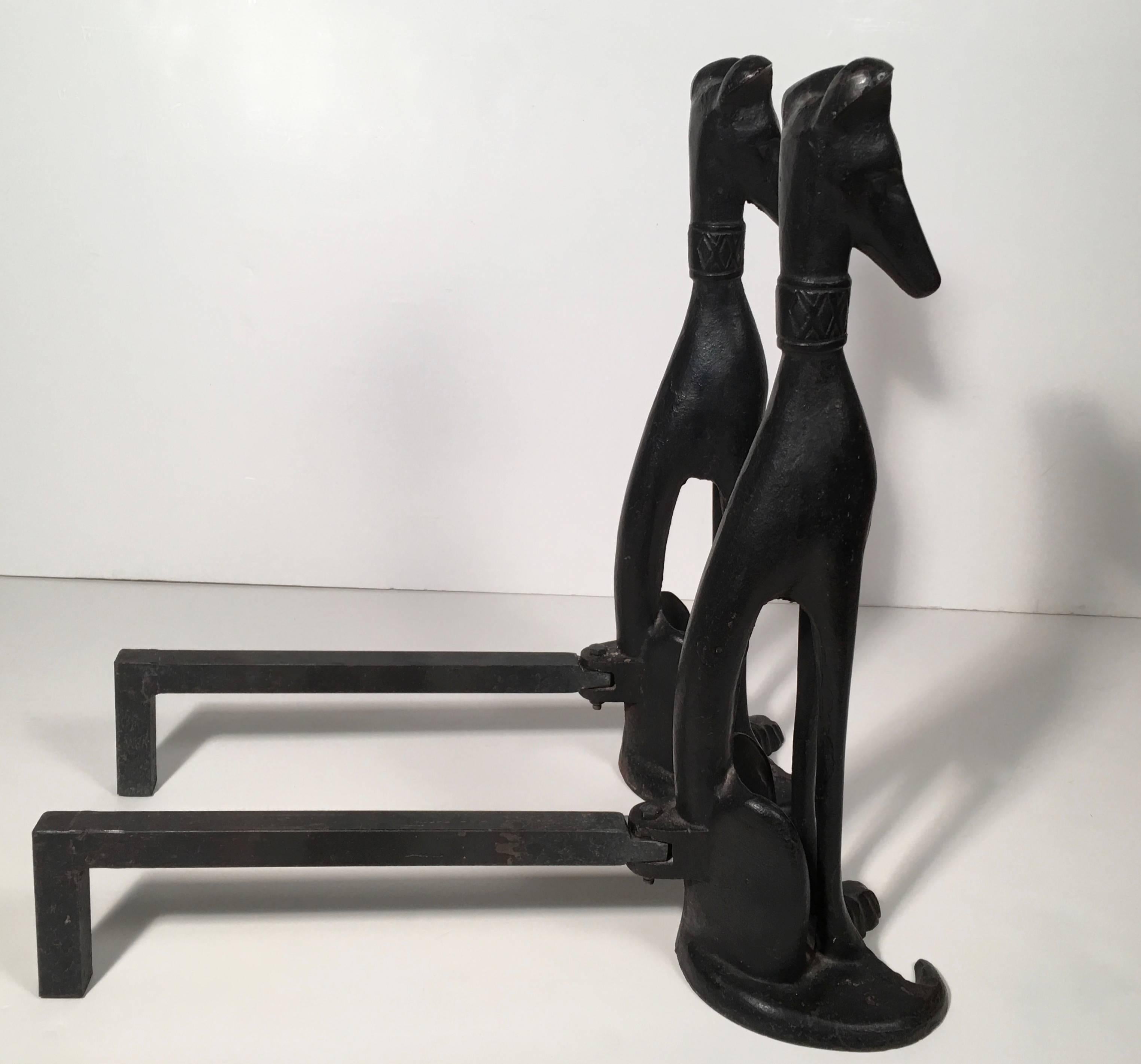 A wonderful pair of Mid-Century, artist made, wrought iron figural dog andirons, each one depicting an alert, stylized dog (whippets or greyhounds, perhaps), with decorative collars, sitting on their haunches, signed 