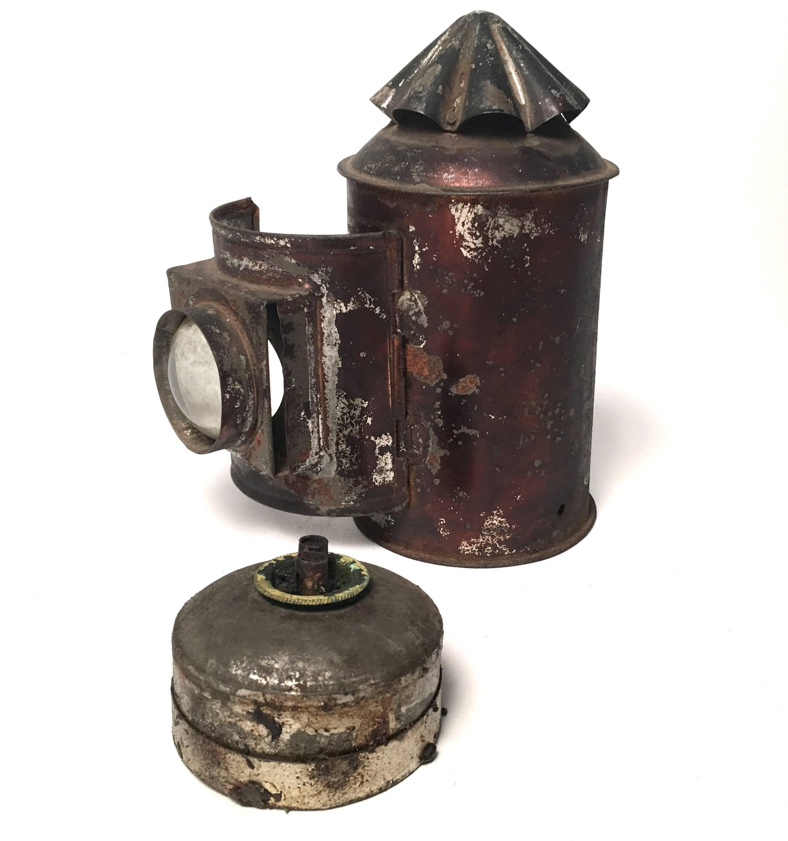A wonderfully preserved and well made tin whale oil lantern from New England, the conical ribbed top with vents, over a cylindrical base with door, embedded with magnifying glass lens, opening to reveal the original removable whale oil canister. A
