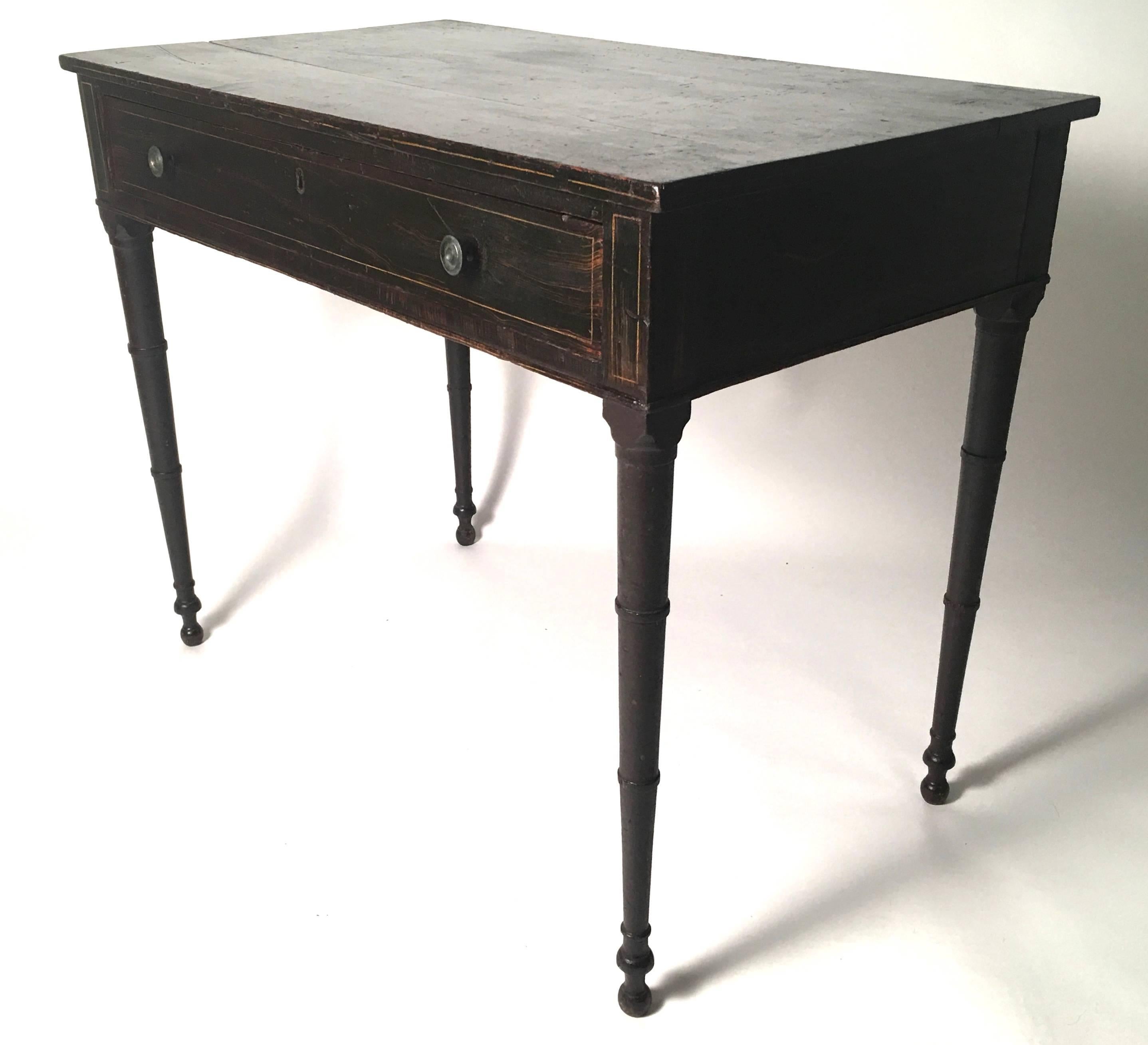 A Federal period grain painted pine one-drawer writing table, of rectangular form, the grain painted top with yellow pinstriped decoration around the perimeter, over a single frieze drawer, retaining its original brass pulls, raised on turned faux