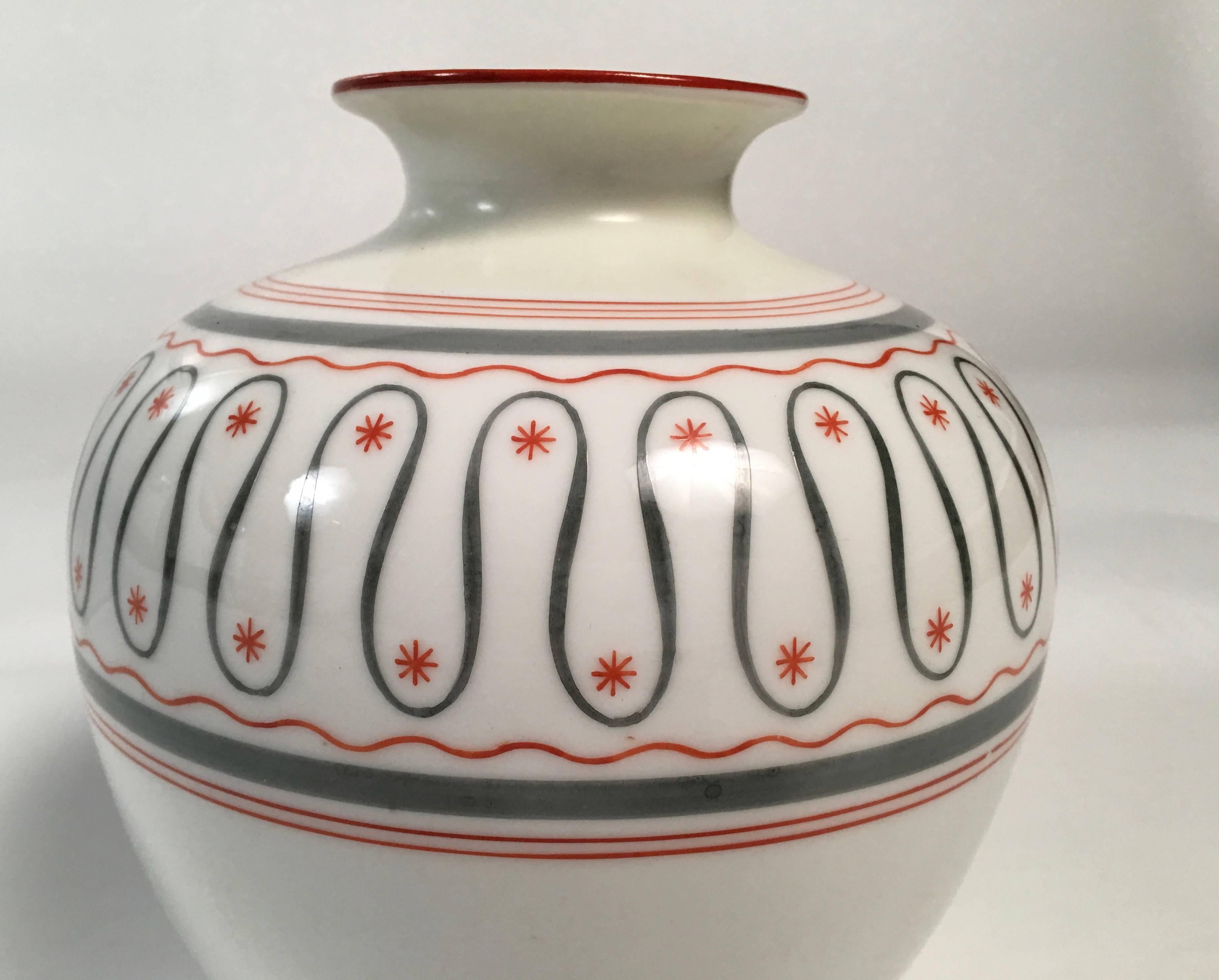 An Art Deco period German white porcelain vase decorated with thin hand-painted bands of gray and orange, centered by a serpentine gray band, with orange stars interspersed. Made by the Friedrich Kaestner, Saxonia porcelain factory, circa 1930s.